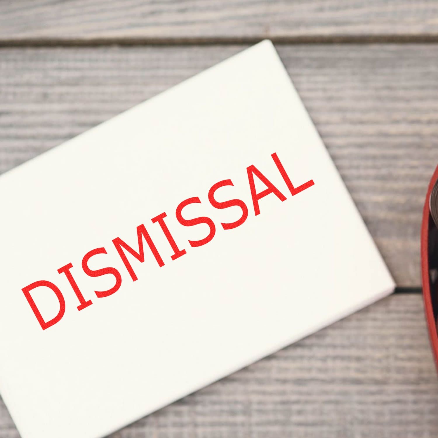 Self Inking Dismissal Stamp imprinting the word DISMISSAL in red ink on a white paper, placed on a wooden surface.