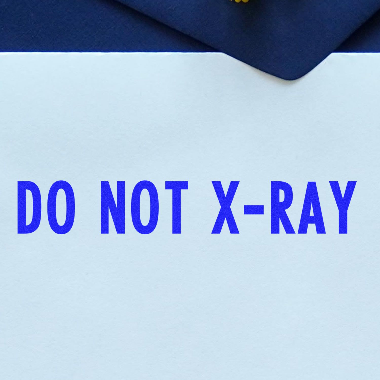 Do Not X-Ray Rubber Stamp imprint in blue ink on a white envelope, with a dark blue background.