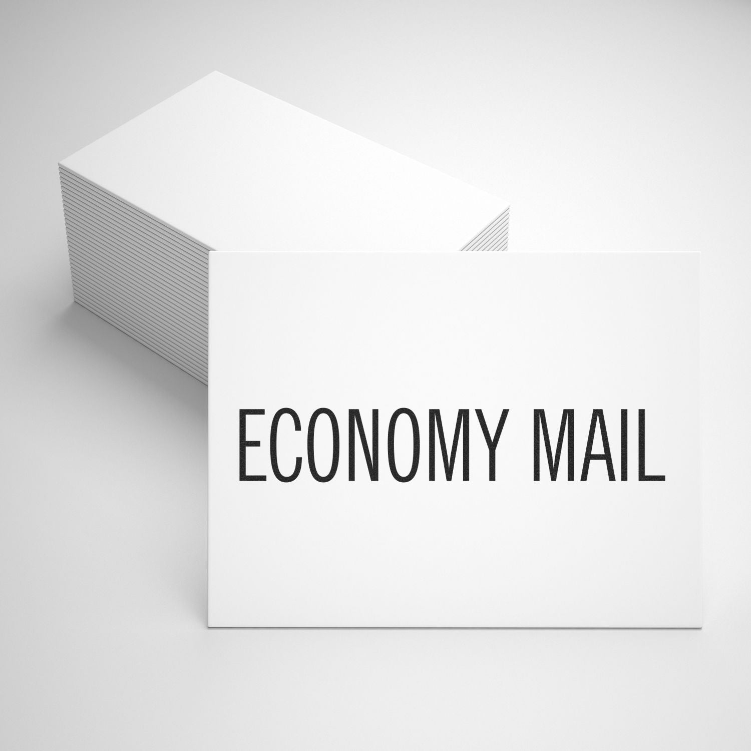 Economy Mail Rubber Stamp in use, stamping ECONOMY MAIL on a stack of white cards, showcasing clear and bold text.