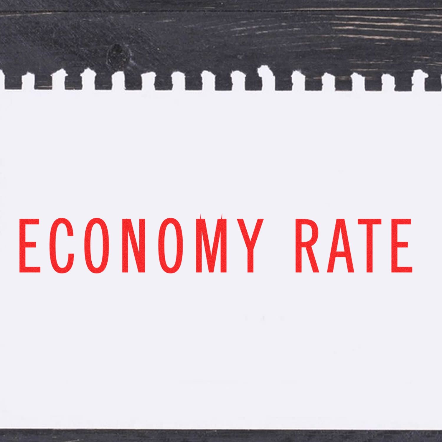 Economy Rate Rubber Stamp imprint in red ink on a white notepad with a black wooden background.