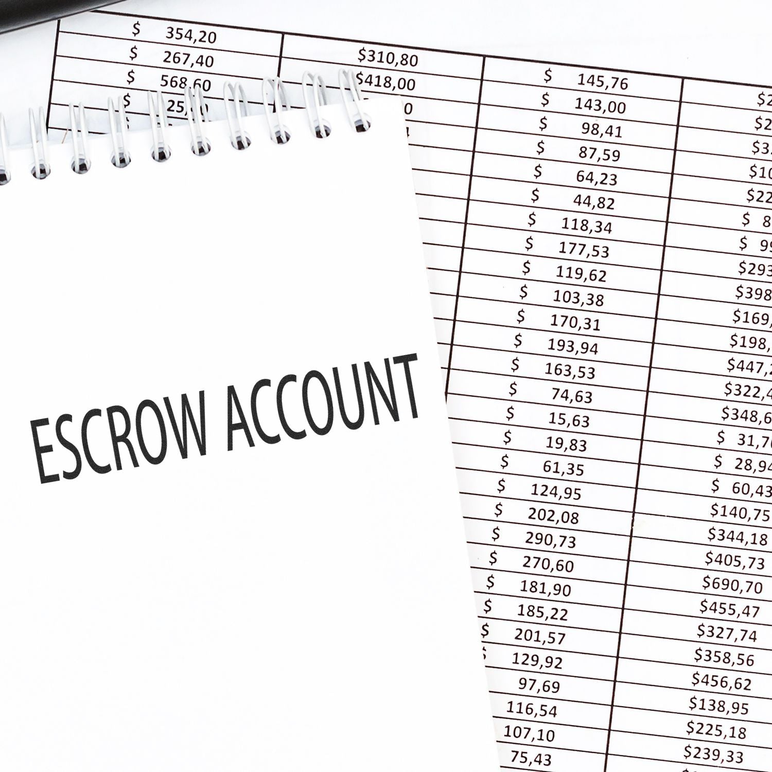 A notebook with Escrow Account written on it, placed on top of a financial spreadsheet, highlighting the use of the Escrow Account Rubber Stamp.