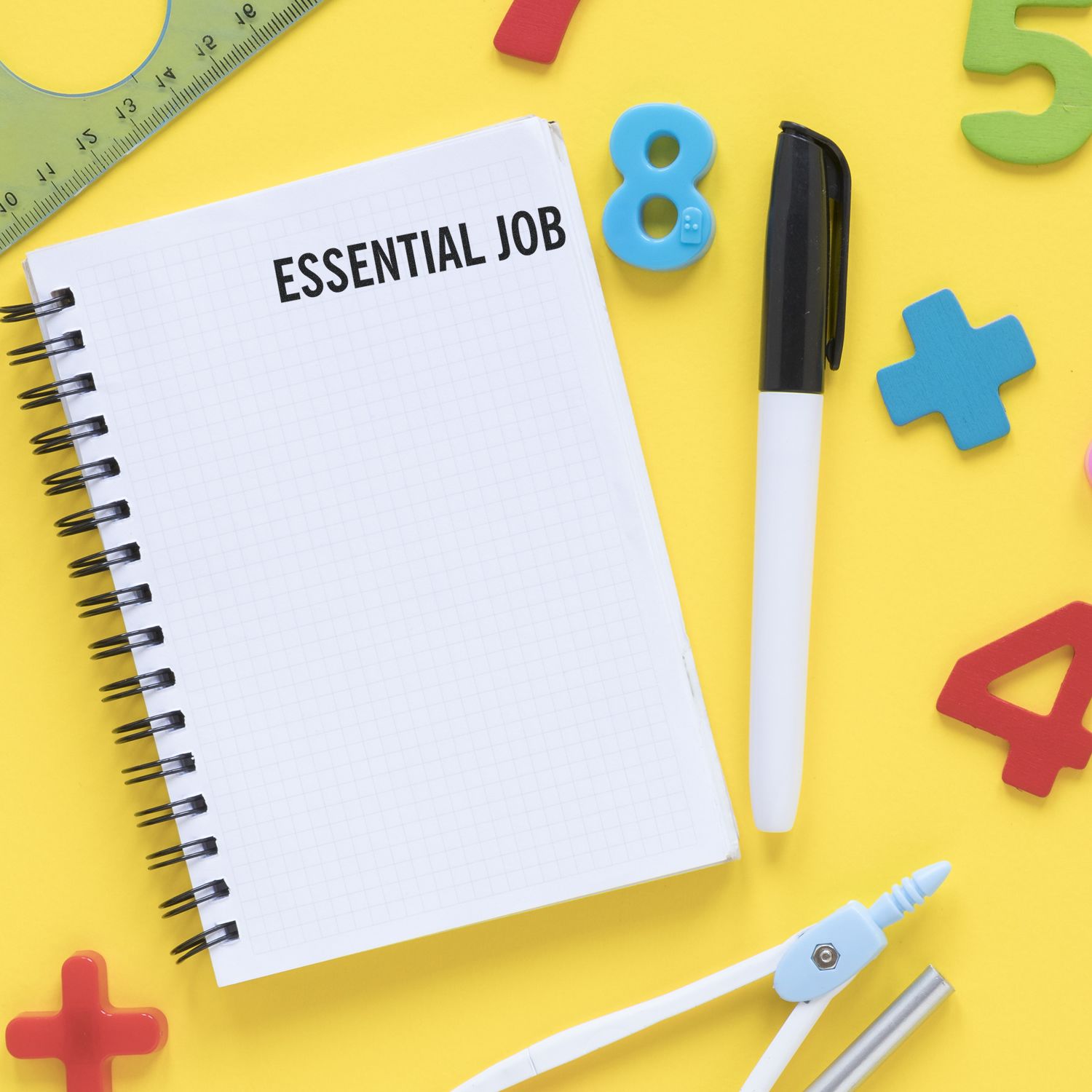 Notebook stamped with ESSENTIAL JOB using the Large Pre-Inked Essential Job Stamp, surrounded by colorful numbers, a pen, and a ruler.