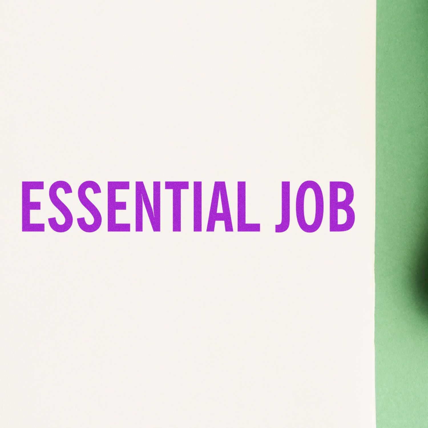 Essential Job Rubber Stamp imprint in bold purple letters on white paper with a green background.