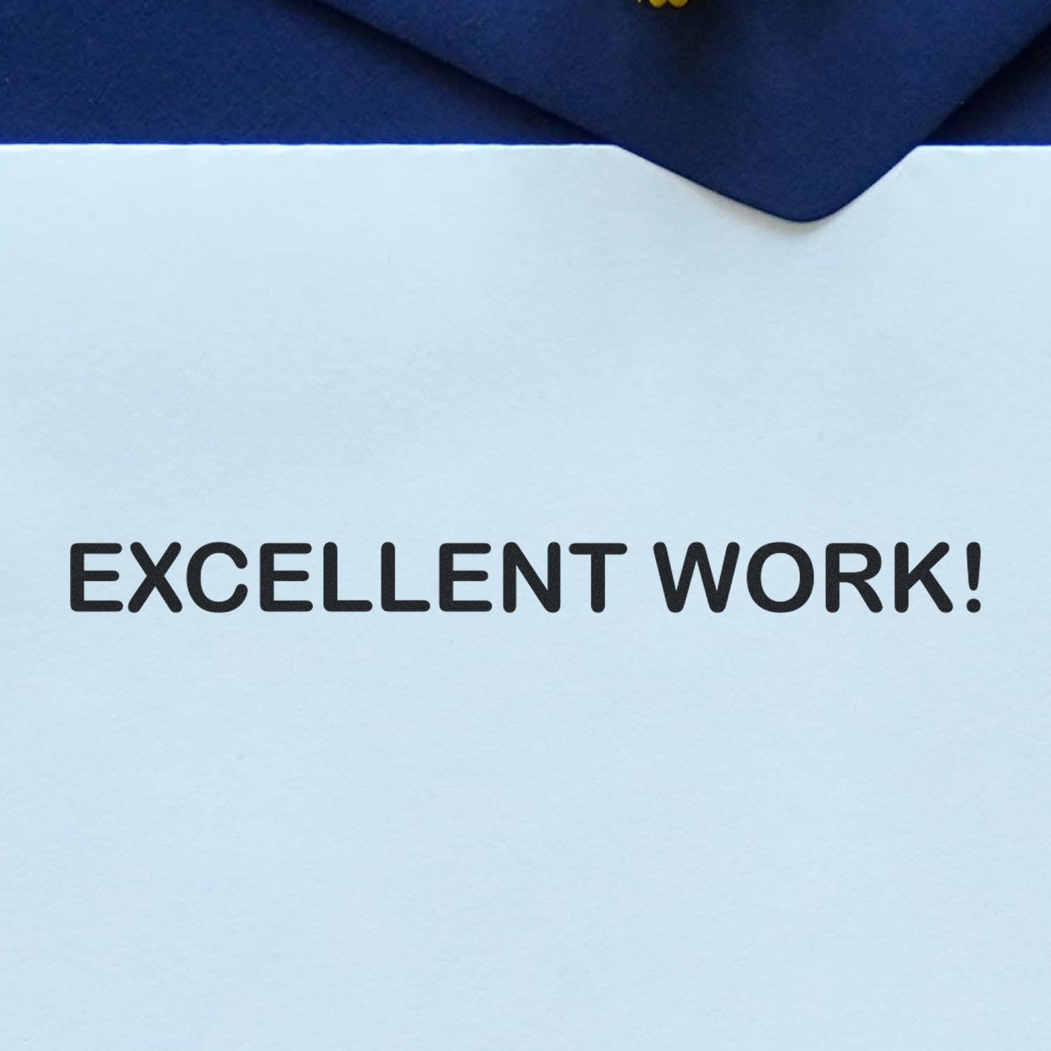 Paper stamped with 'EXCELLENT WORK!' using the Self Inking Excellent Work Stamp, placed on a dark blue background.