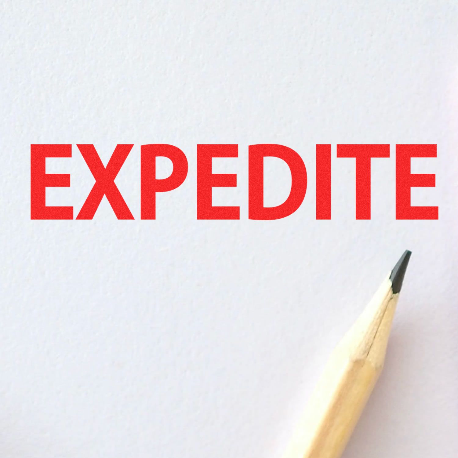 Expedite Rubber Stamp in use, showing the word 'EXPEDITE' stamped in red ink on white paper with a pencil tip visible at the bottom right.