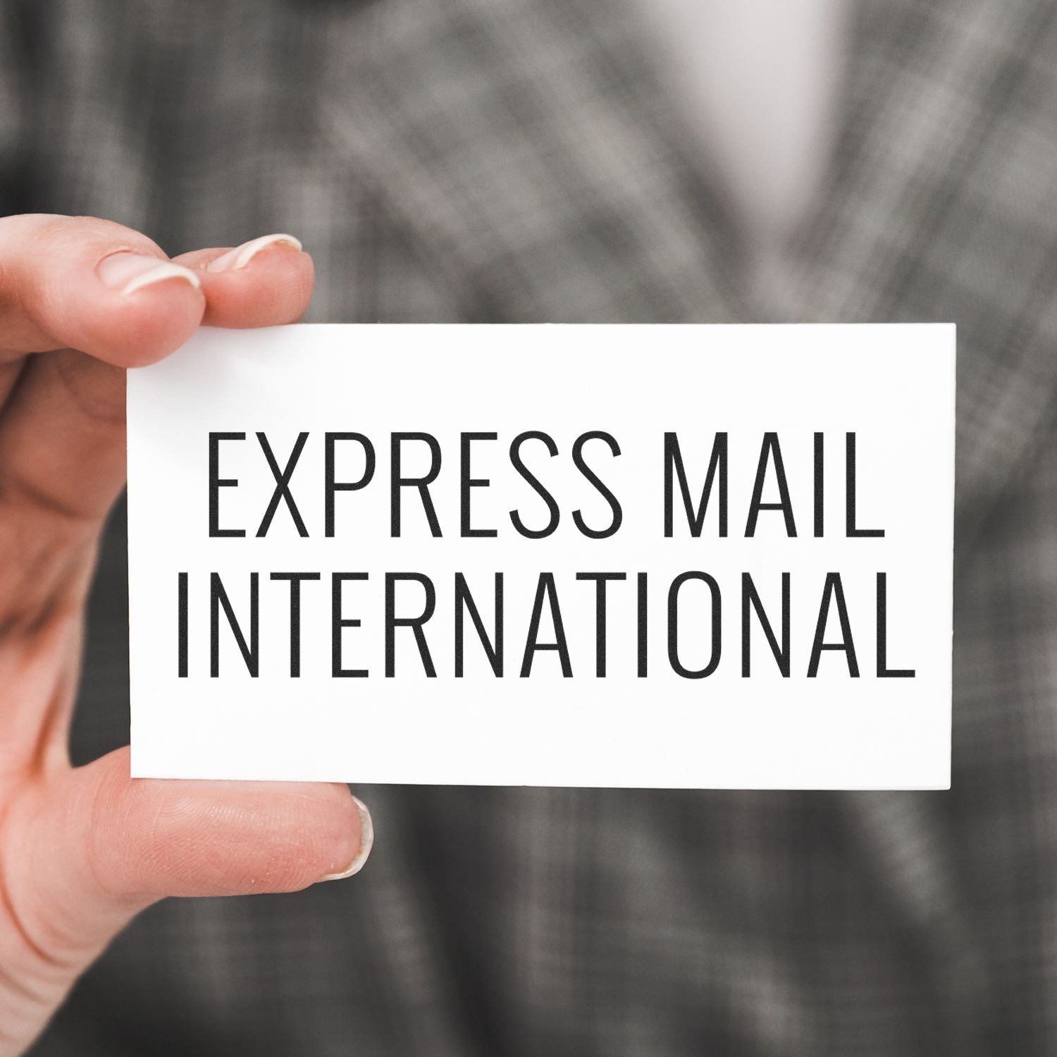 A hand holding a white card with the text EXPRESS MAIL INTERNATIONAL stamped on it using the Express Mail International Rubber Stamp.