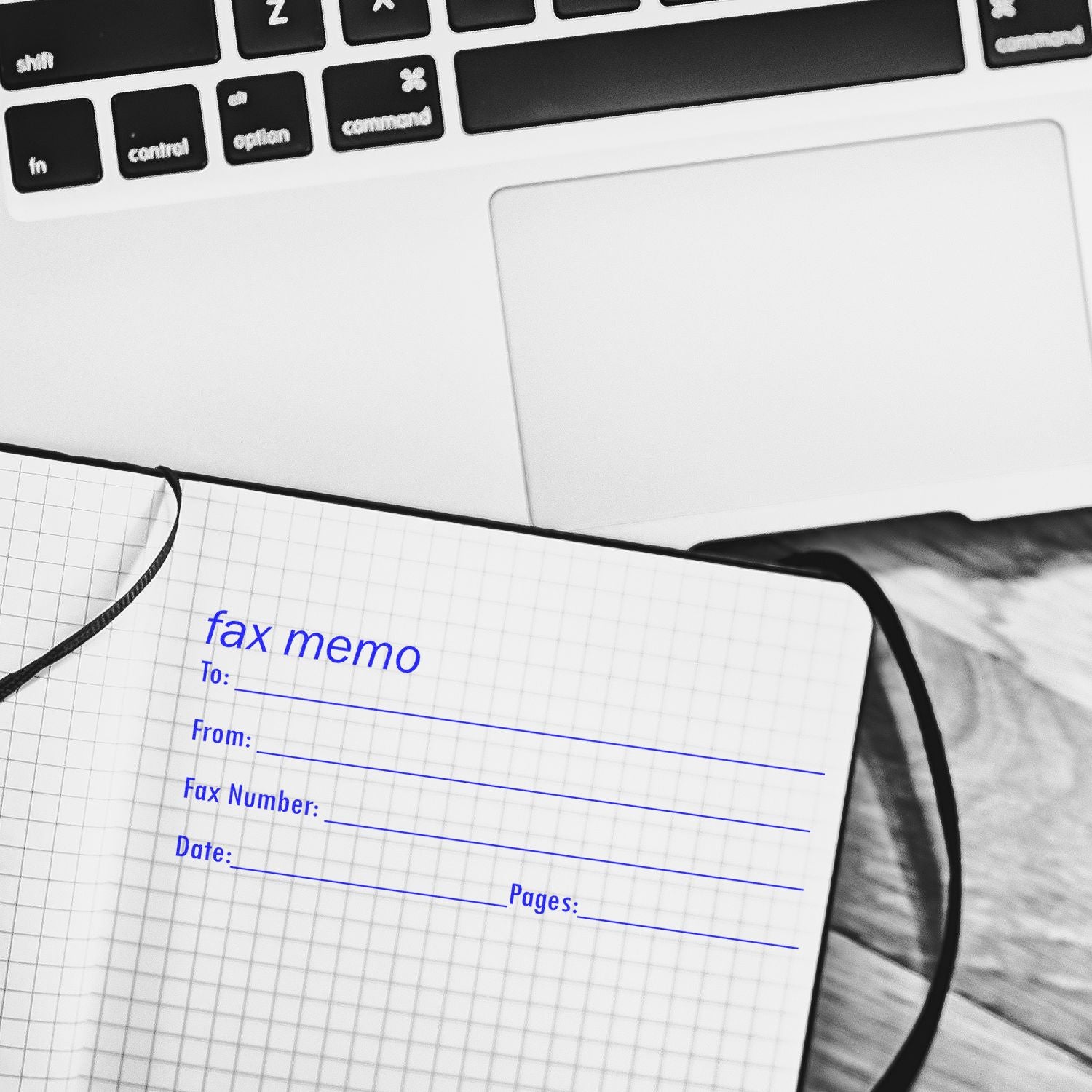 A notebook stamped with fax memo using the Fax It 2 Rubber Stamp, placed next to a laptop on a wooden surface.