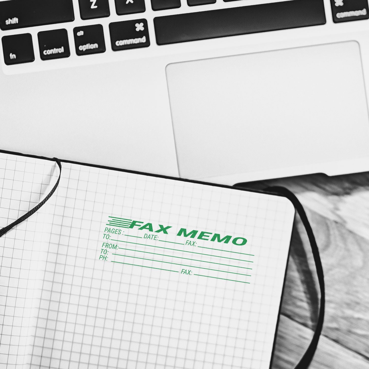 Notebook stamped with Large Fax Memo Rubber Stamp, placed next to a laptop on a wooden desk.