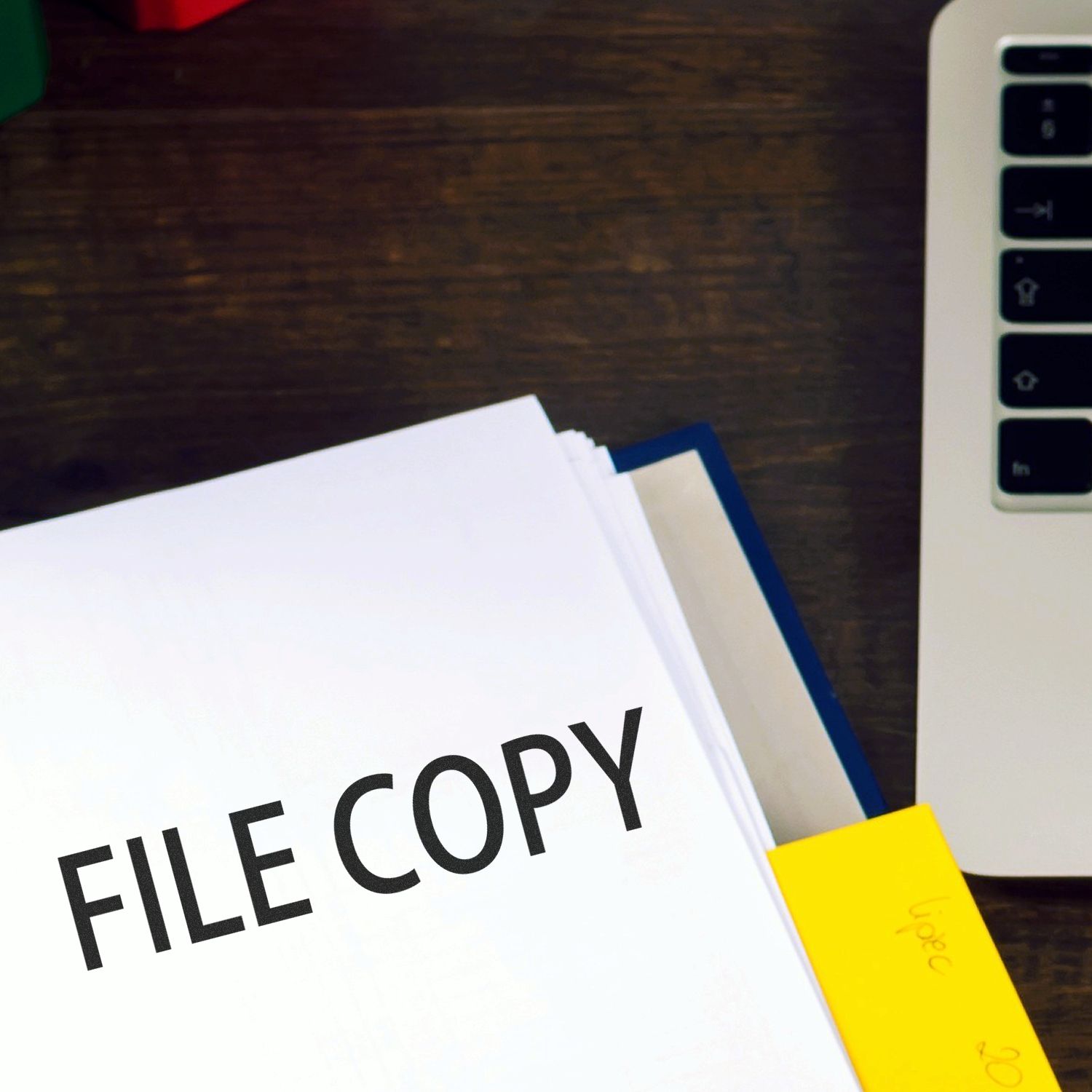 Large Self Inking File Copy Stamp marking a document on a desk next to a laptop and a yellow sticky note.