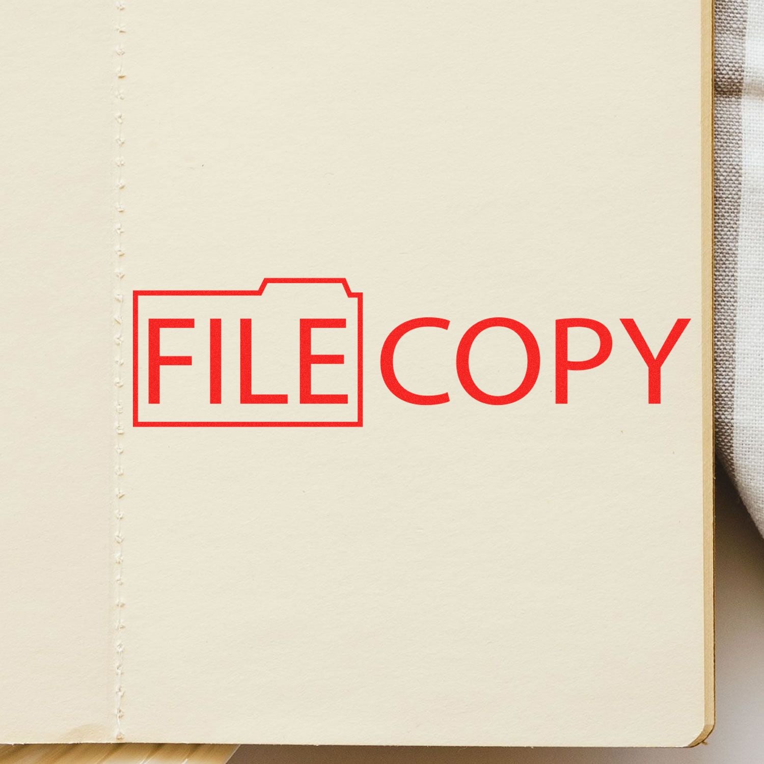 File Copy with Folder Rubber Stamp in red ink on a beige paper, showing the text FILE COPY with a folder icon around the word FILE .