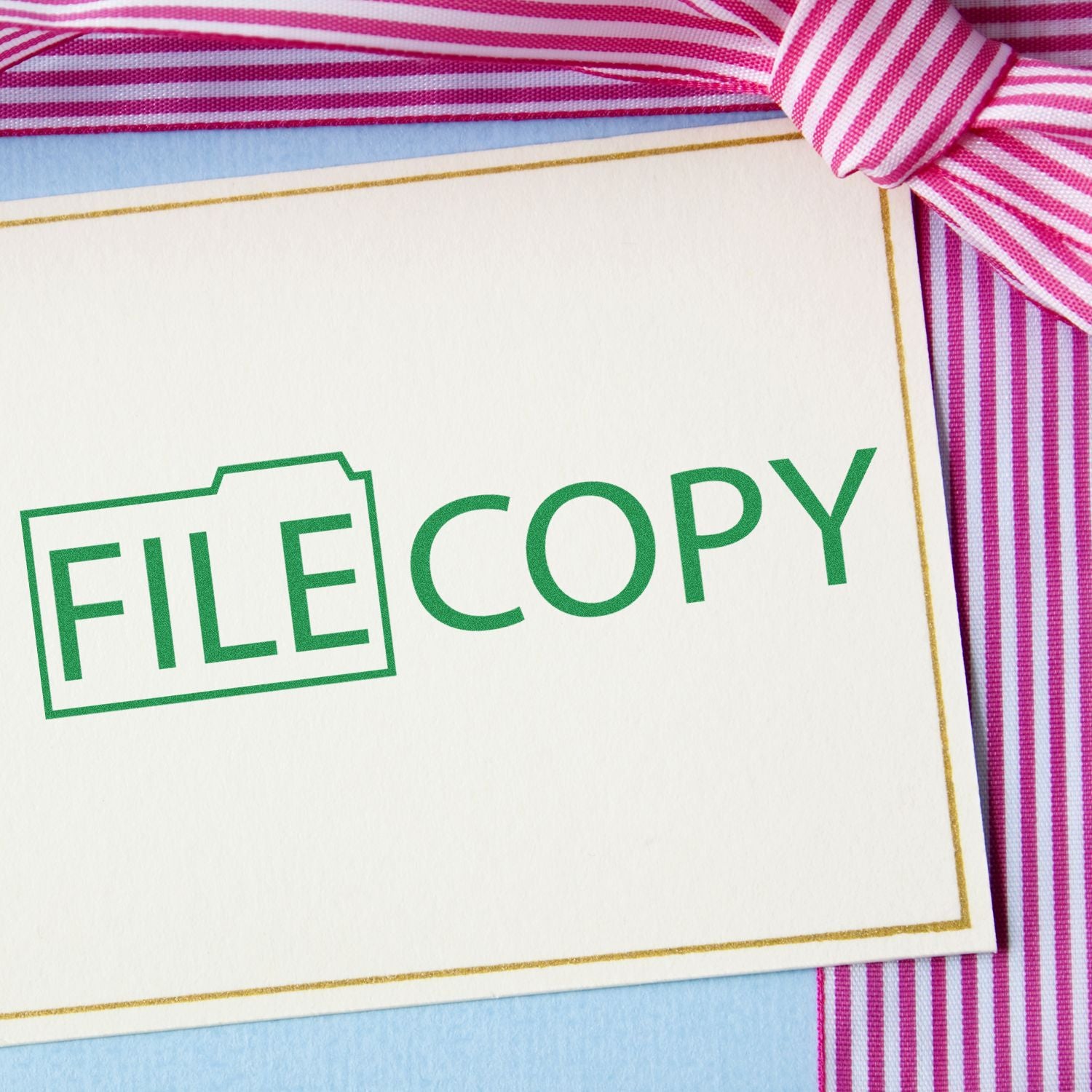 File Copy with Folder Rubber Stamp on a white card with pink and white striped ribbon in the background.