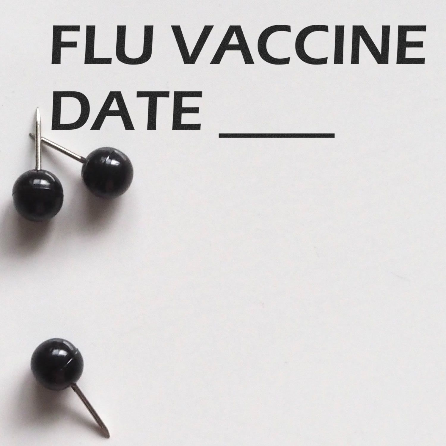 Self Inking Flu Vaccine Date Stamp in use, with black push pins on white paper displaying FLU VACCINE DATE and a blank line for the date.