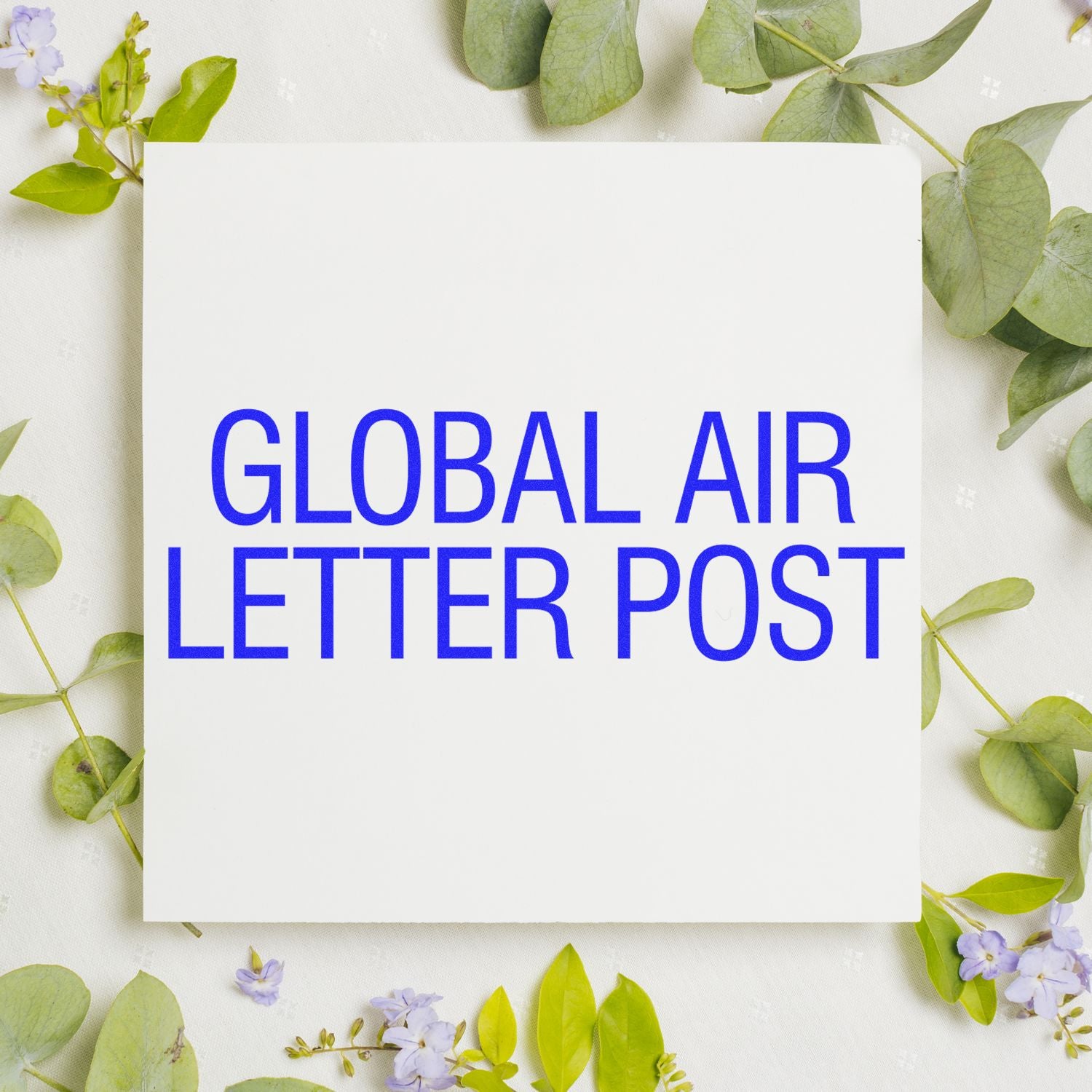 Global Air Letter Post Rubber Stamp in blue ink on white paper, surrounded by green leaves and small purple flowers.