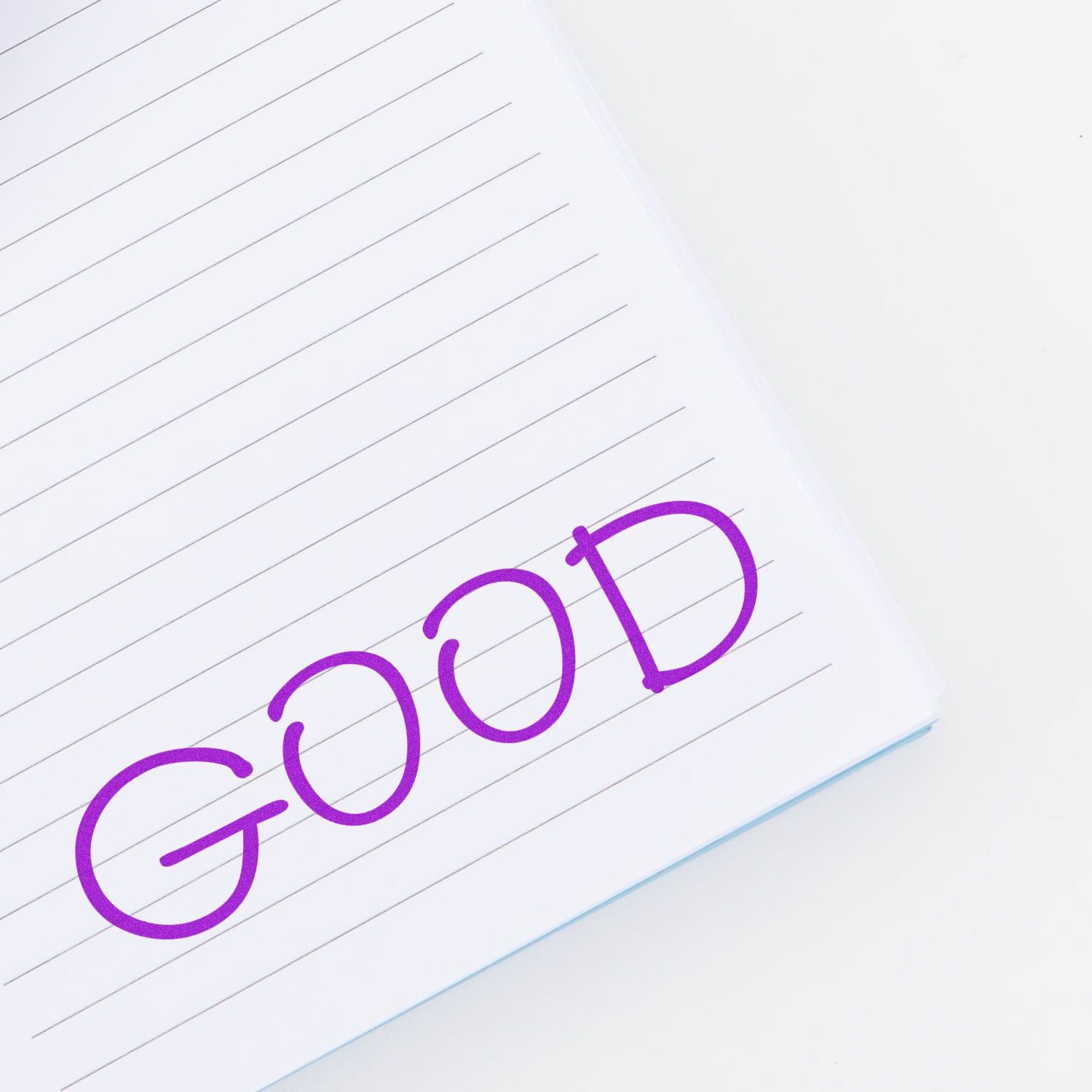 Large Self Inking Good Stamp imprinting the word GOOD in purple ink on a lined notebook page.