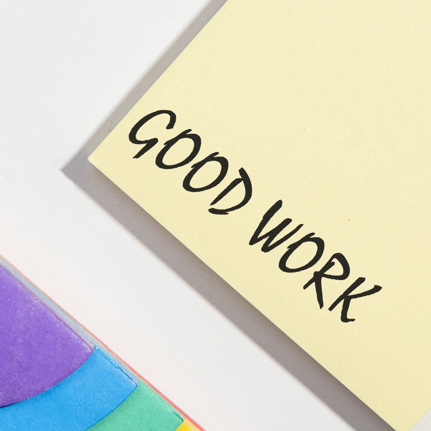 Good Work Rubber Stamp impression on a yellow paper, with colorful sticky notes partially visible in the corner.