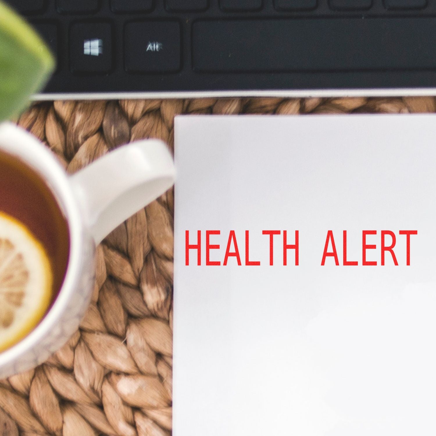 Large Self Inking Health Alert Stamp used on white paper, next to a cup of tea with a lemon slice and a keyboard in the background.