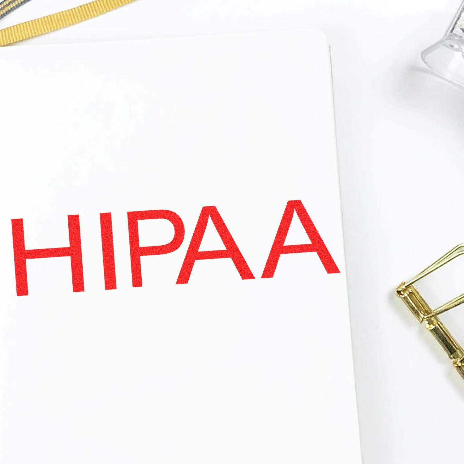 HIPAA Medical Rubber Stamp imprint in red on a white paper, with part of a gold paperclip and a clear stamp holder visible.