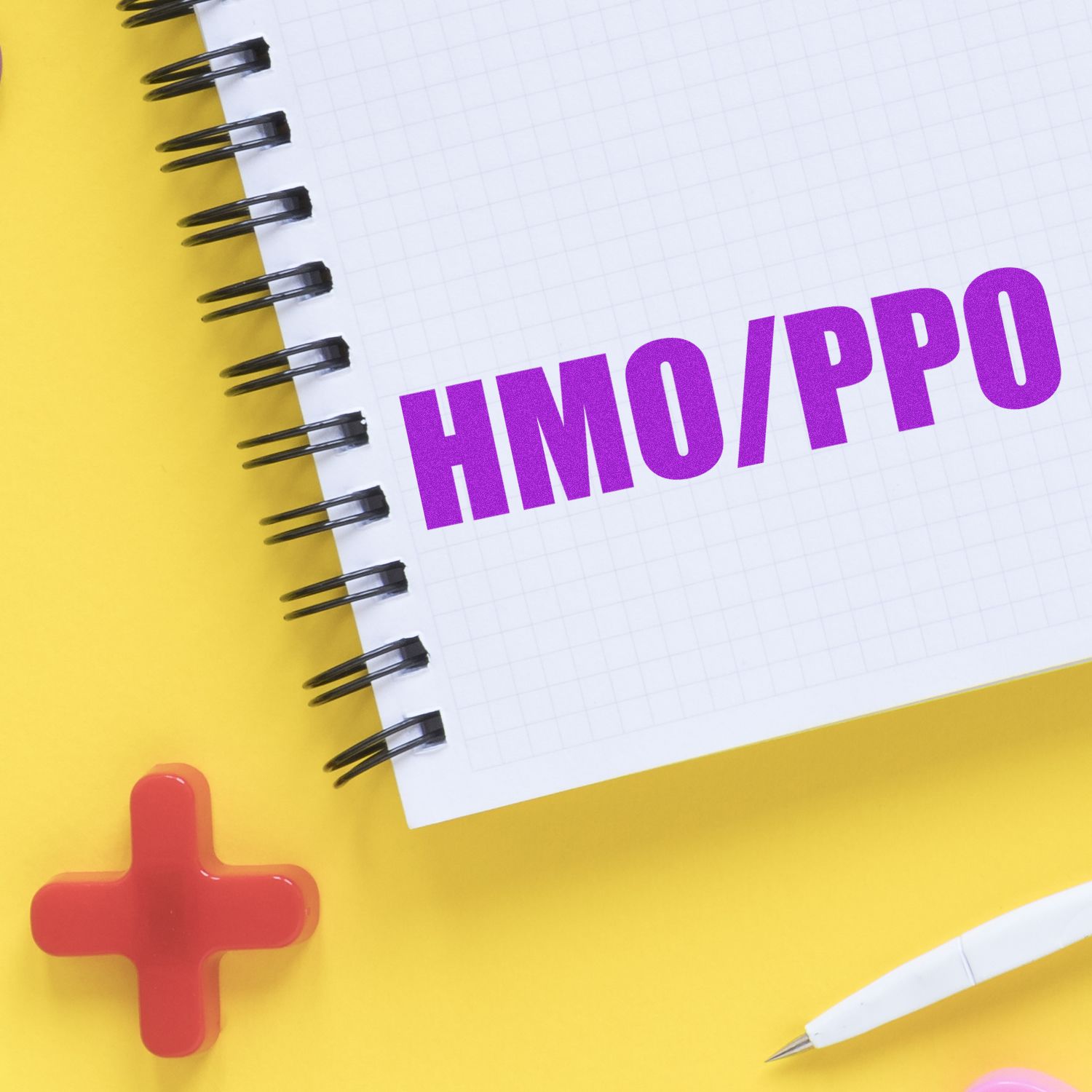 Self Inking HMO/PPO Stamp used on a spiral notebook with a yellow background, red cross symbol, and white pen nearby.