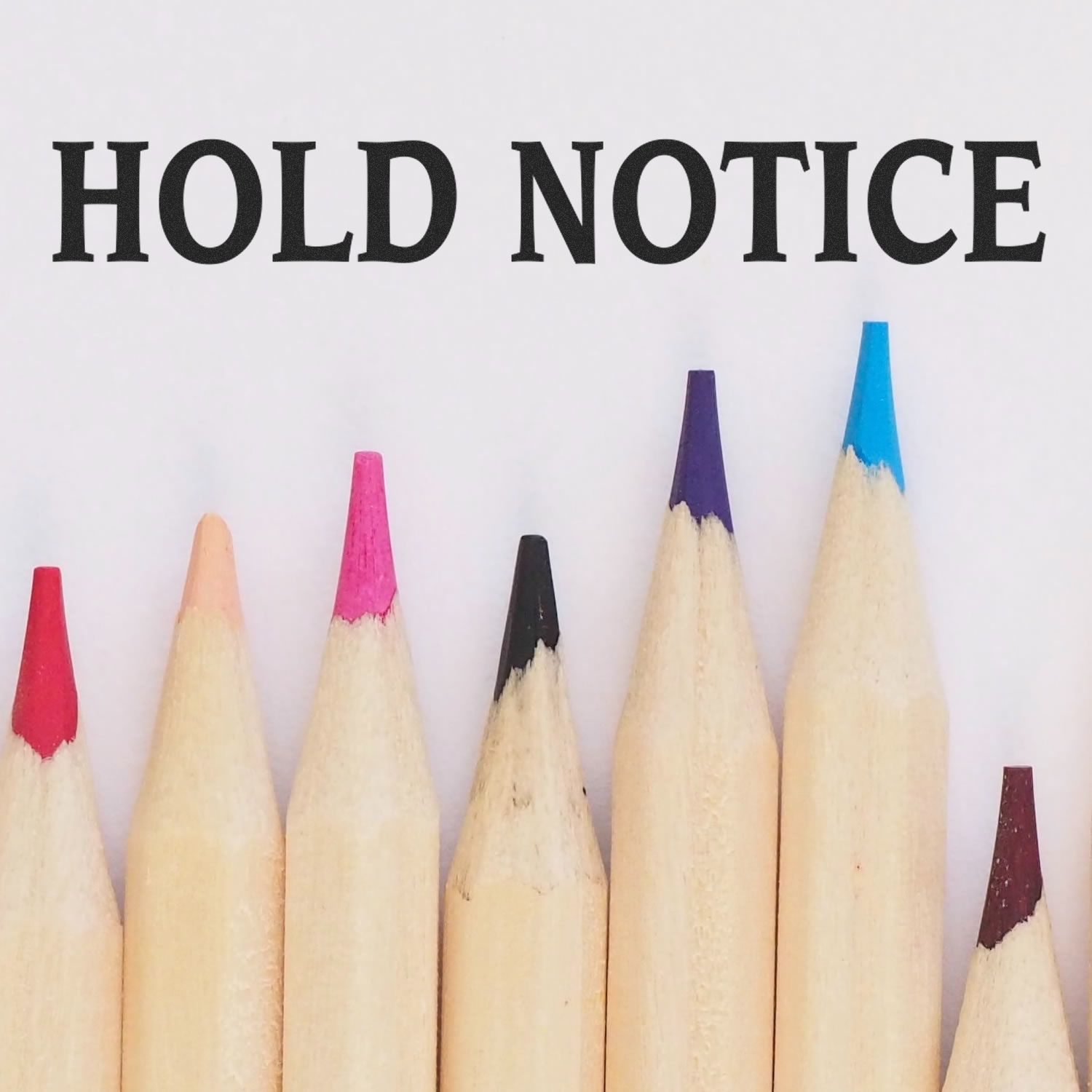 Large Pre-Inked Hold Notice Stamp in use, with the words HOLD NOTICE stamped above a row of colorful pencil tips.