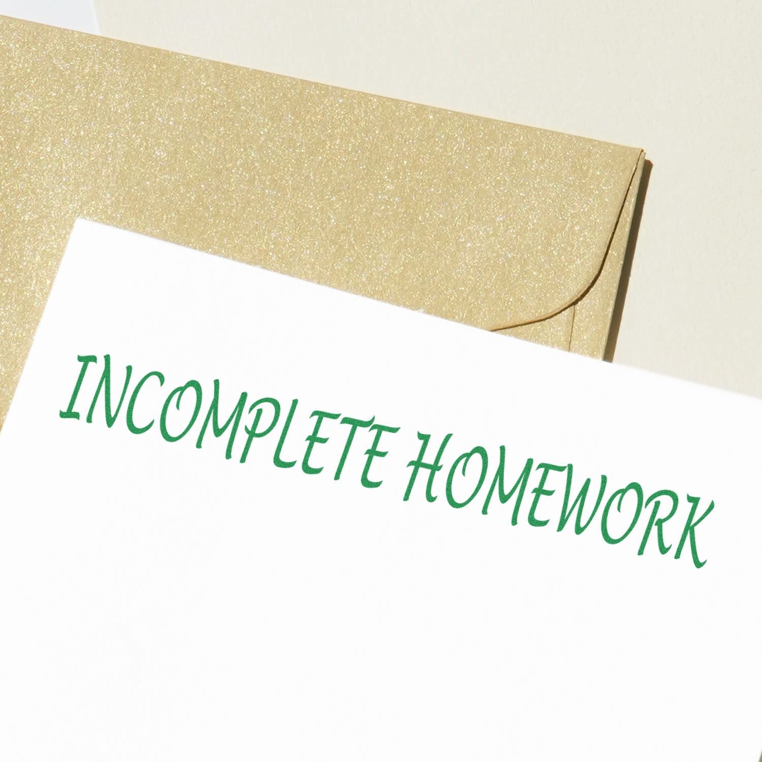 A paper stamped with INCOMPLETE HOMEWORK in green ink using the Incomplete Homework Rubber Stamp, placed on a golden envelope.