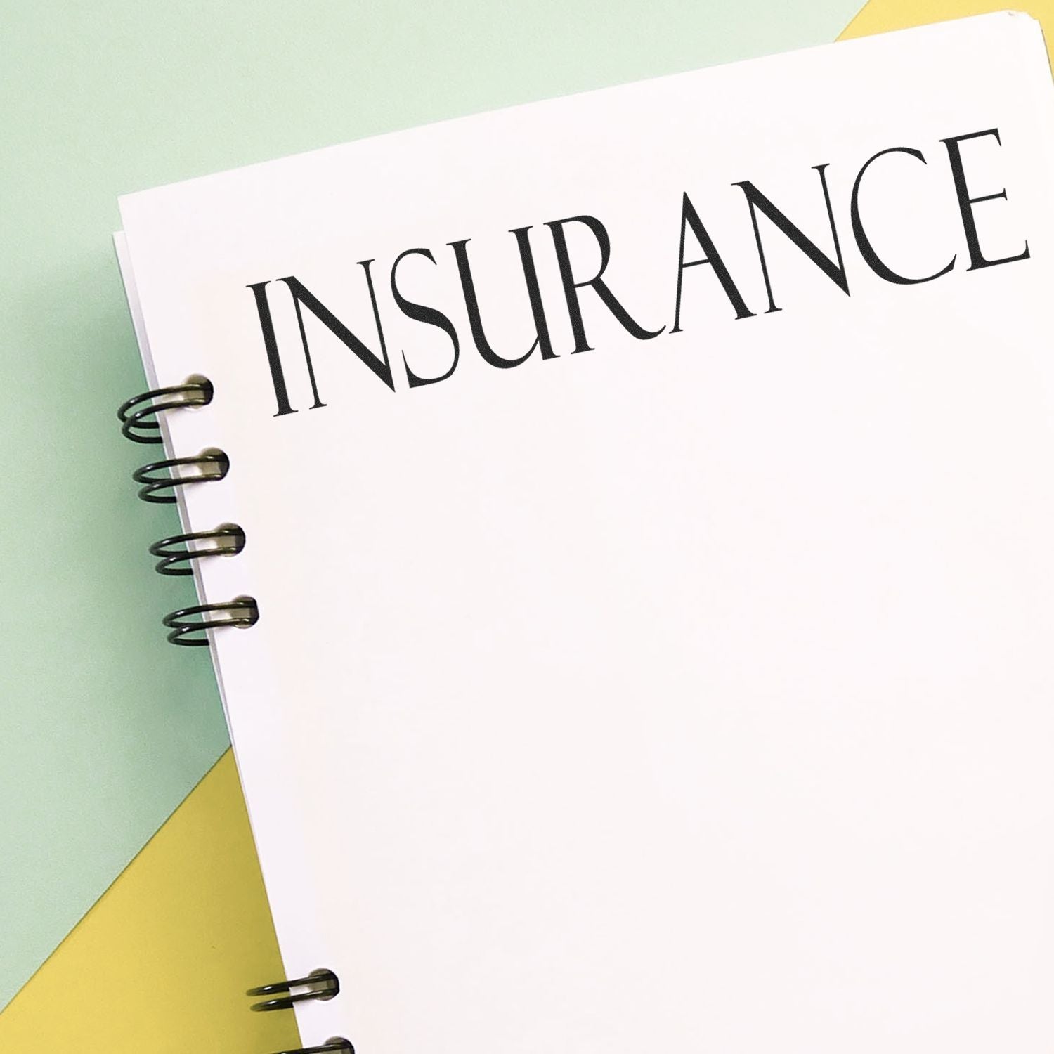 A Slim Pre-Inked Insurance Stamp is used on a white spiral-bound insurance document, placed on a pastel background.