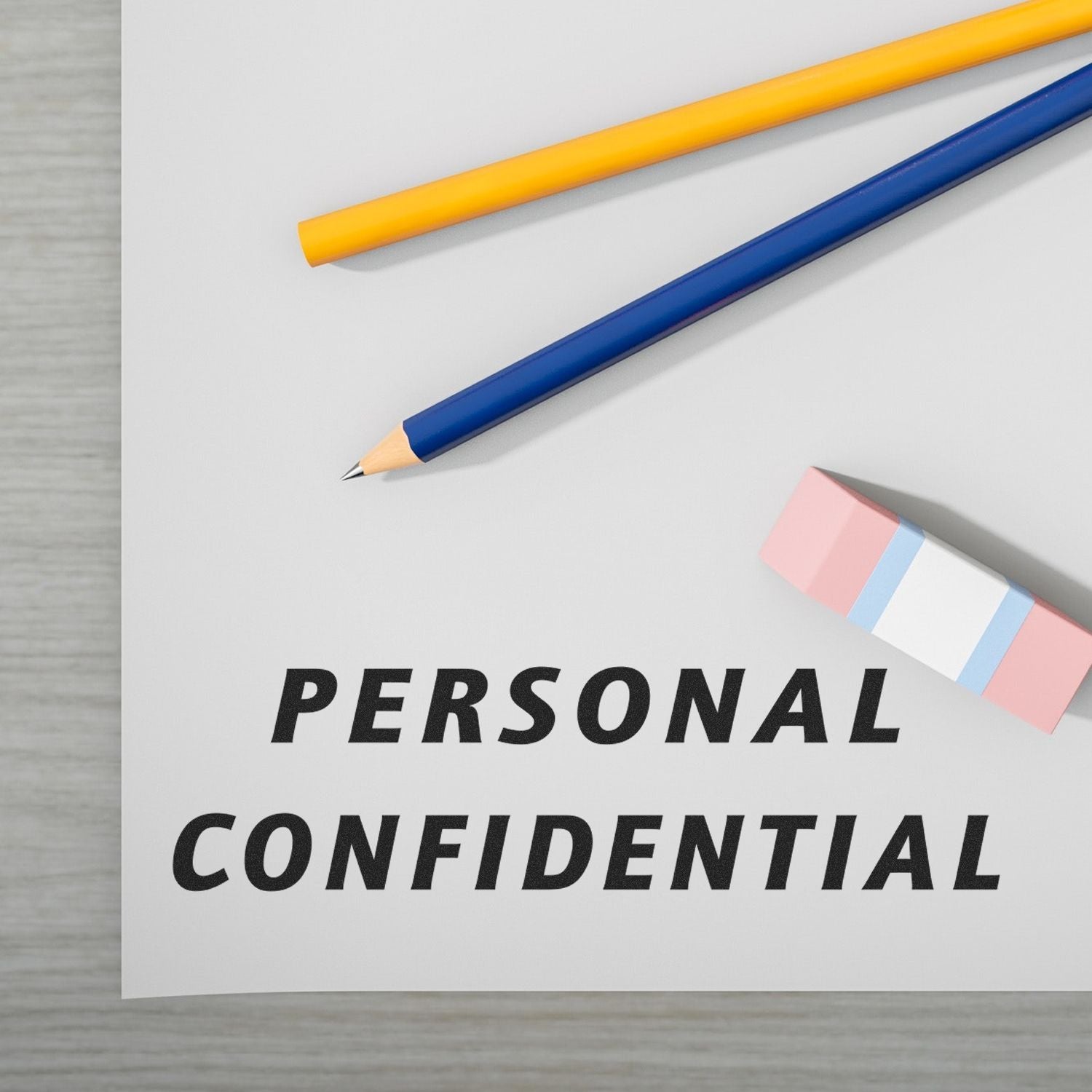 Large Italic Personal Confidential Rubber Stamp imprint on paper, with a pencil, pen, and eraser placed nearby on a wooden surface.