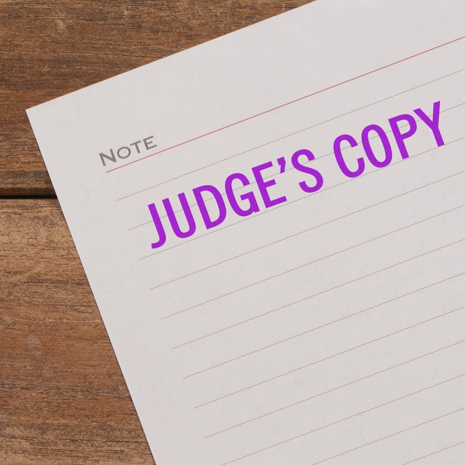 A piece of paper stamped with Judge's Copy in purple ink using the Judge's Copy Rubber Stamp, placed on a wooden surface.