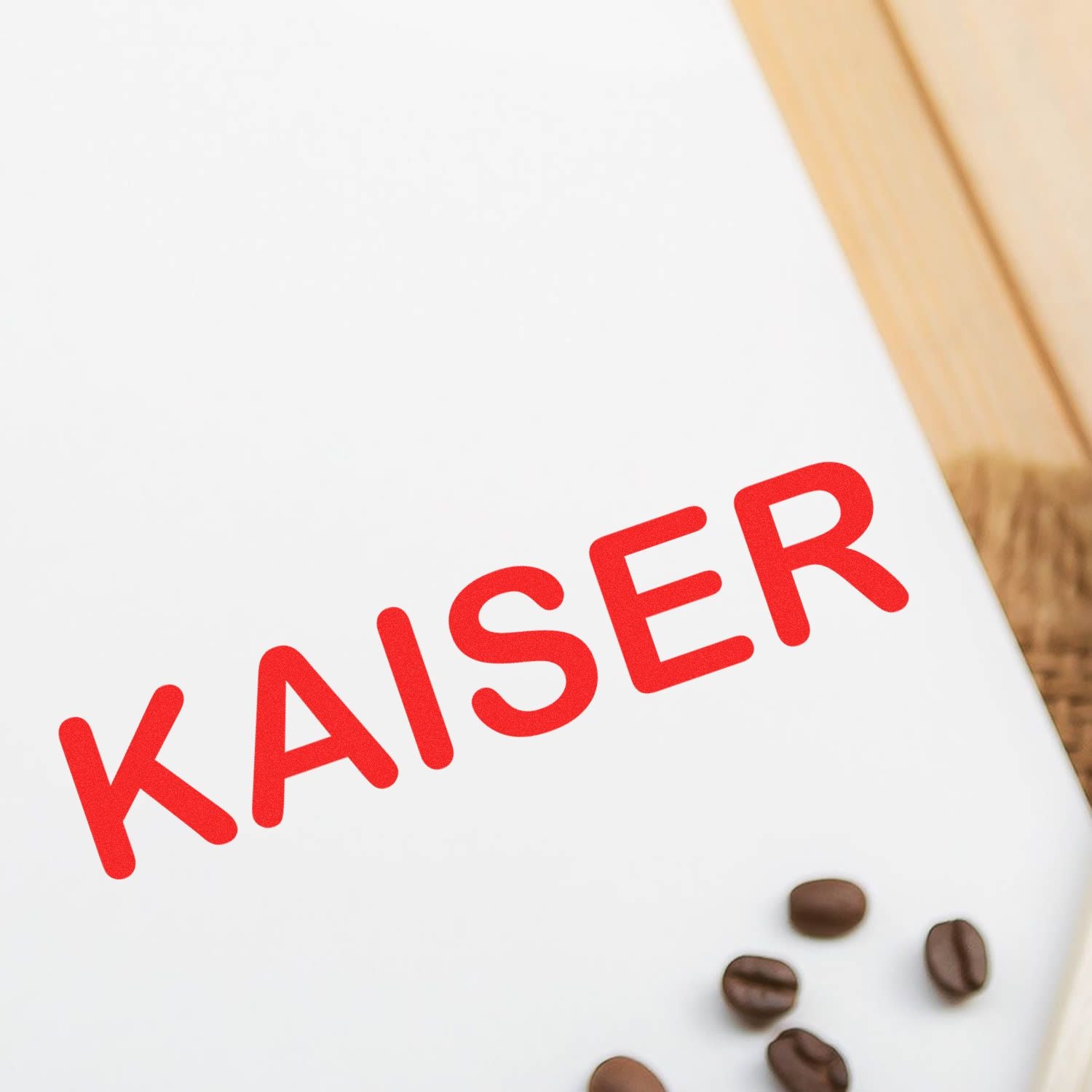 Medical Kaiser Rubber Stamp imprint in red ink on white paper with coffee beans nearby on a wooden surface.