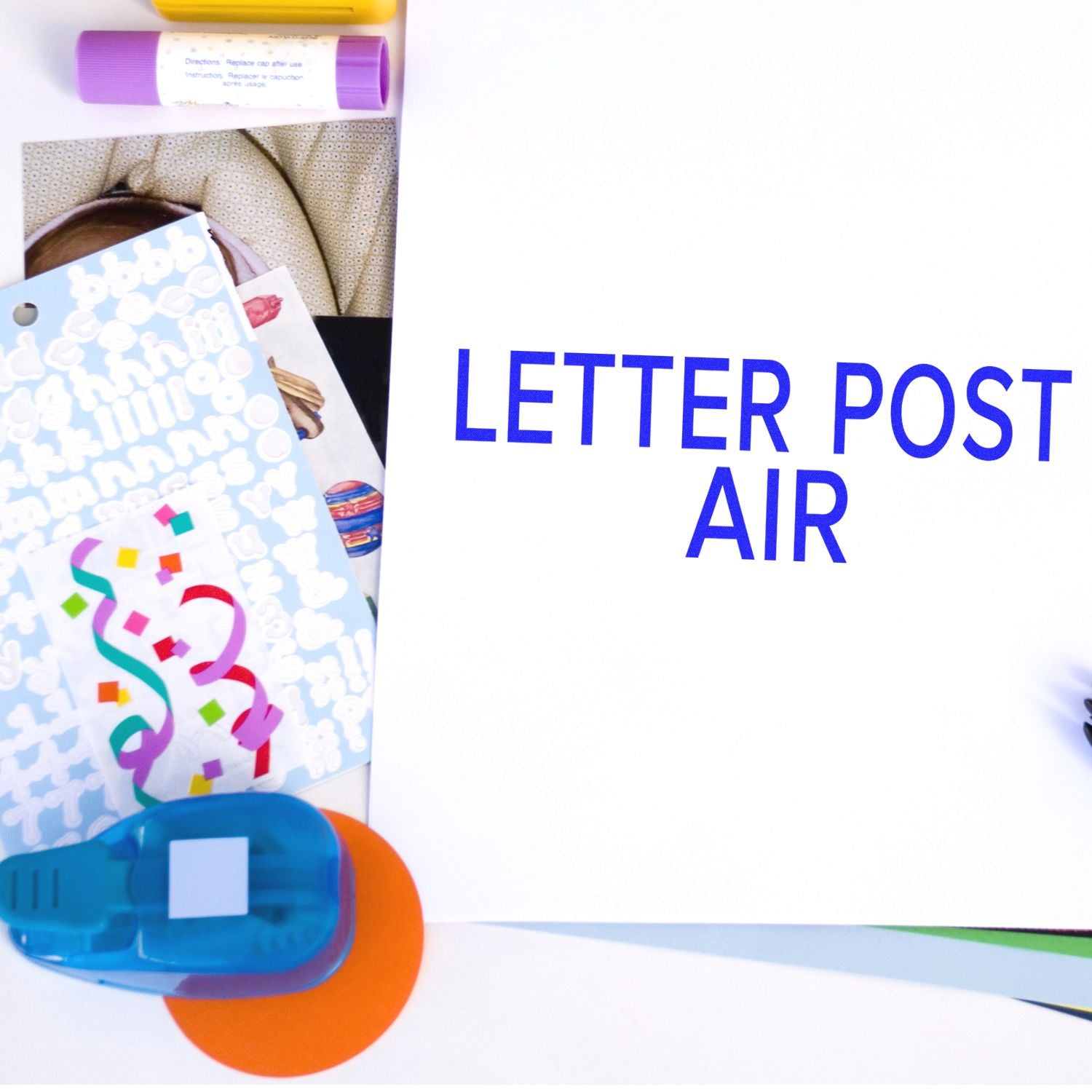 Large Letter Post Air Rubber Stamp in use on white paper, surrounded by colorful stationery items including stickers, glue, and a hole punch.