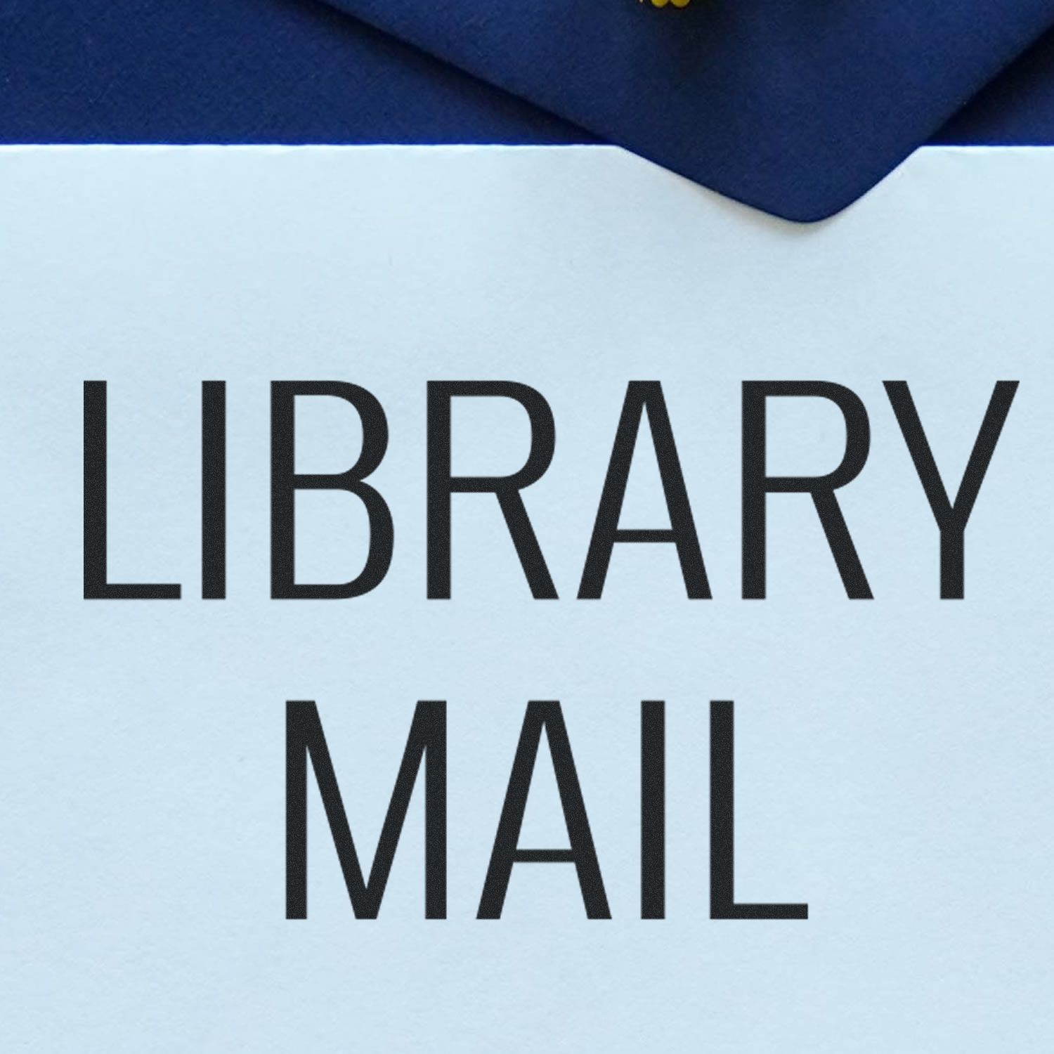 Library Mail Rubber Stamp impression on a light blue envelope with a dark blue background.