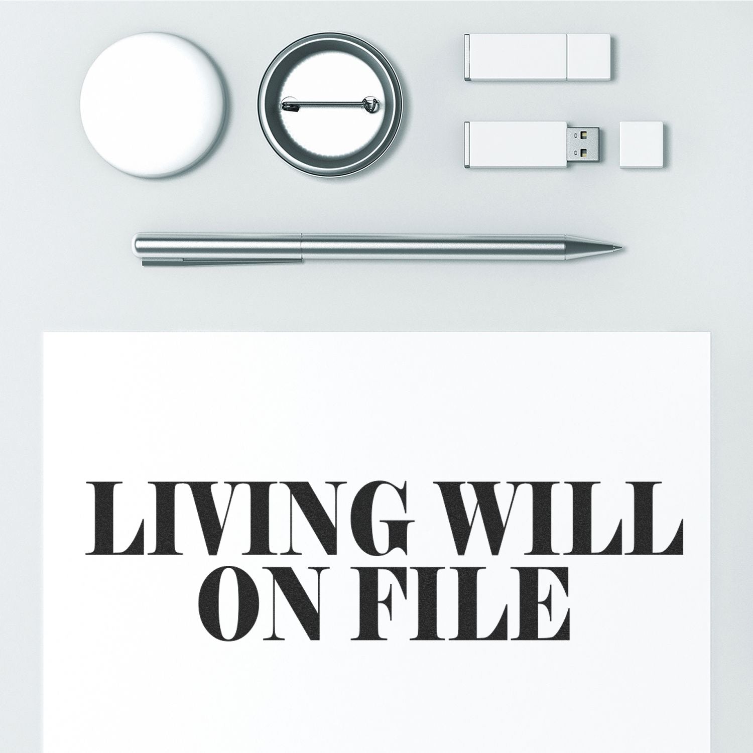 Large Pre-Inked Living Will On File Stamp used on a document, surrounded by office supplies including a pen, USB drives, and a badge.