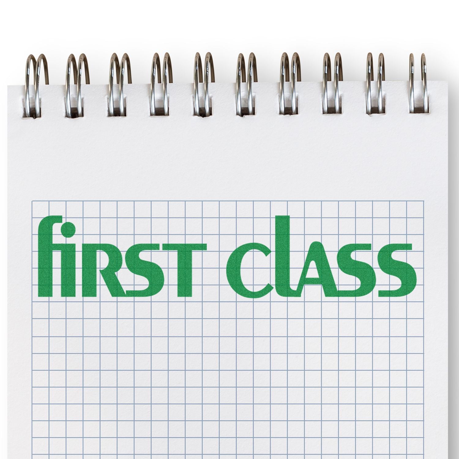 Large Lower Case First Class Rubber Stamp in green ink on a spiral-bound graph paper notebook.