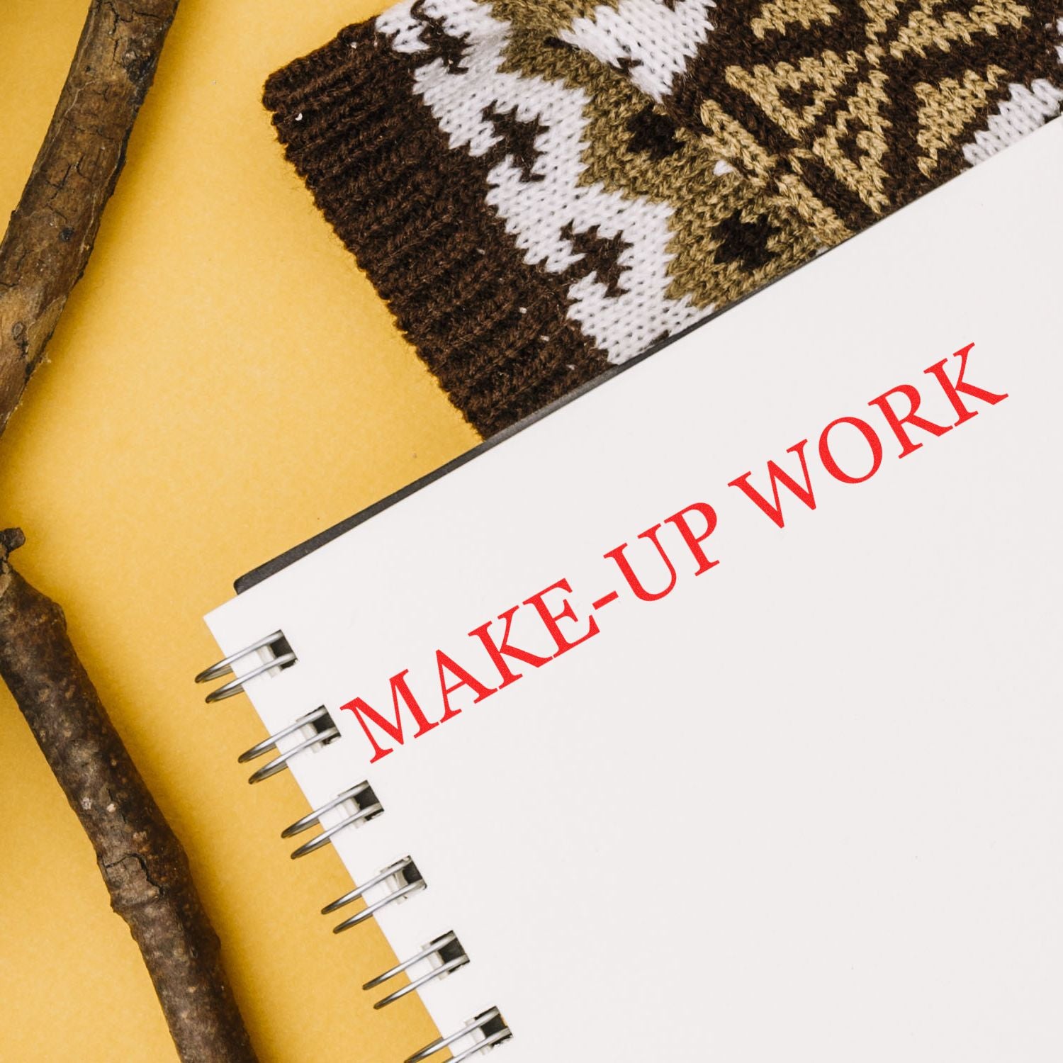 Large Pre-Inked Make-Up Work Stamp used on a notebook with a knitted item and wooden sticks in the background.