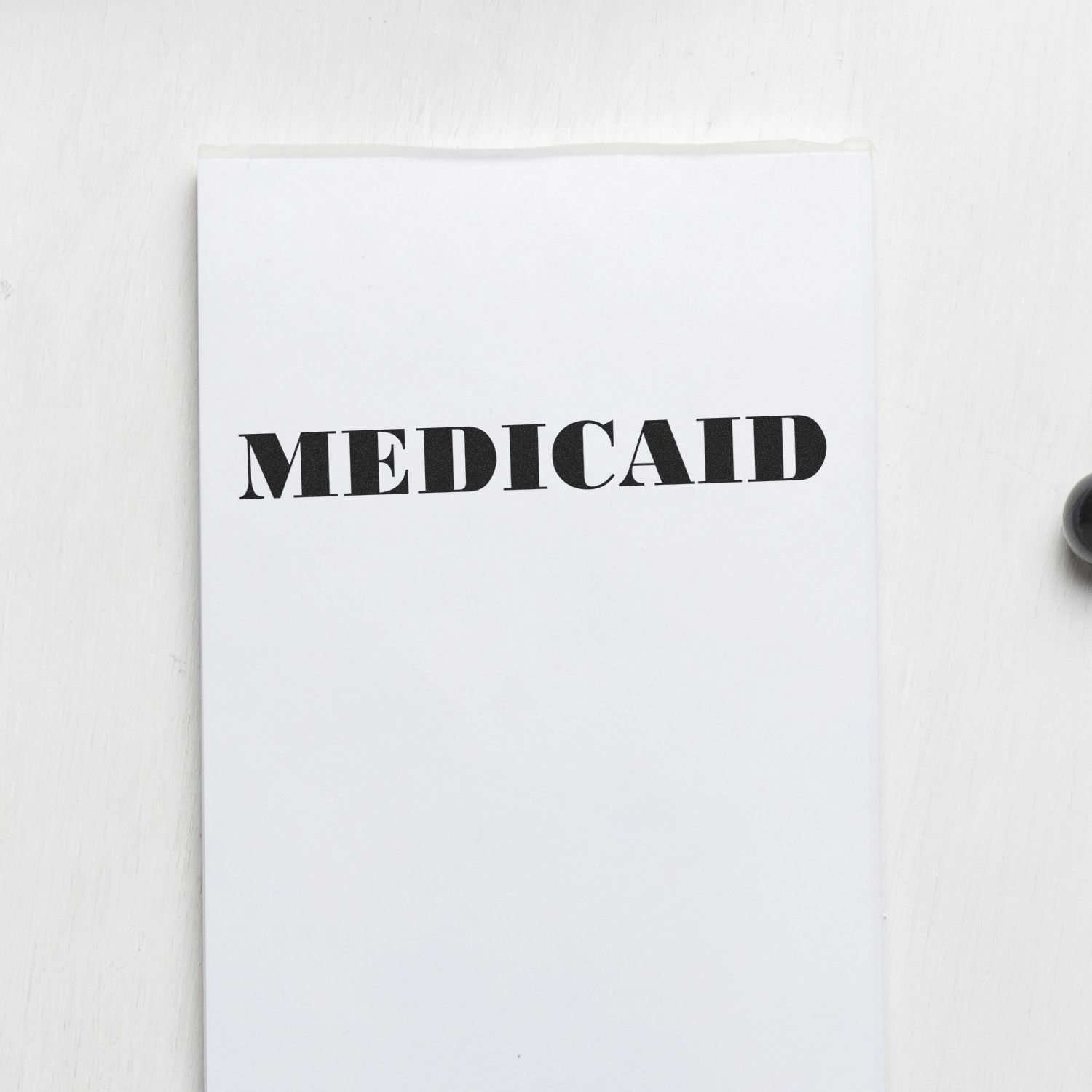 Large Medicaid Rubber Stamp imprinting the word MEDICAID in bold black letters on a white sheet of paper.