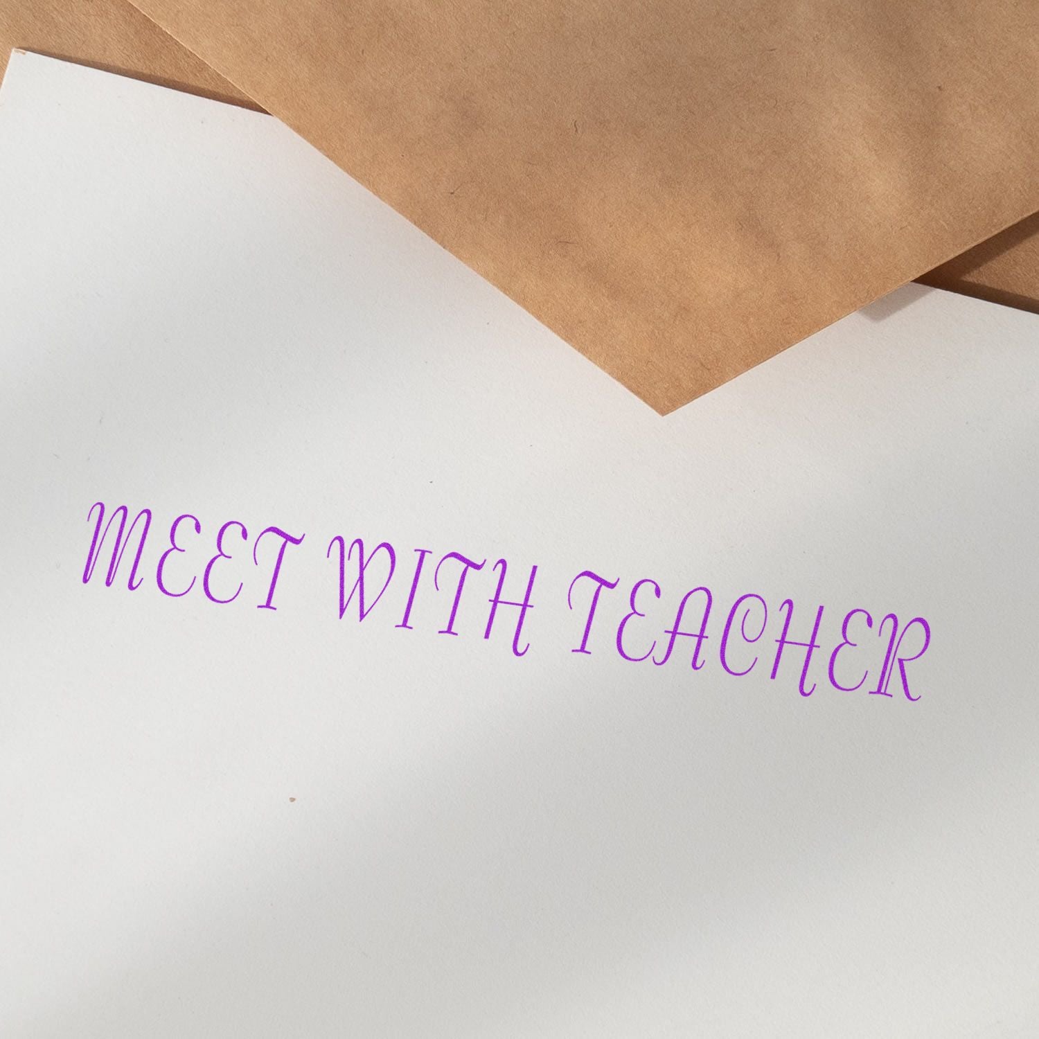 Paper stamped with 'MEET WITH TEACHER' in purple ink using a Slim Pre-Inked Meet With Teacher Stamp, with brown envelopes nearby.