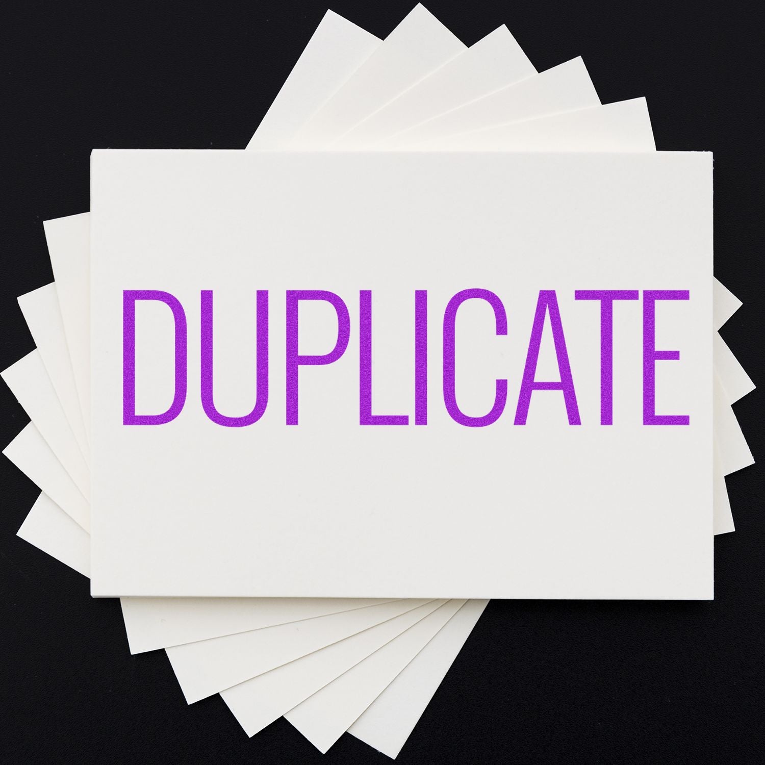 Slim Pre-Inked Narrow Font Duplicate Stamp in purple ink on white cards, fanned out on a black background.