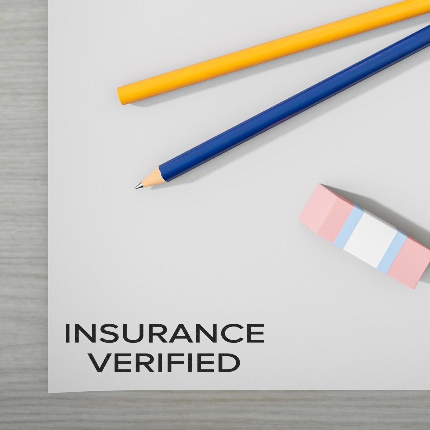 Narrow Font Insurance Verified rubber stamp on paper with a yellow pencil, blue pencil, and pink eraser on a wooden surface.