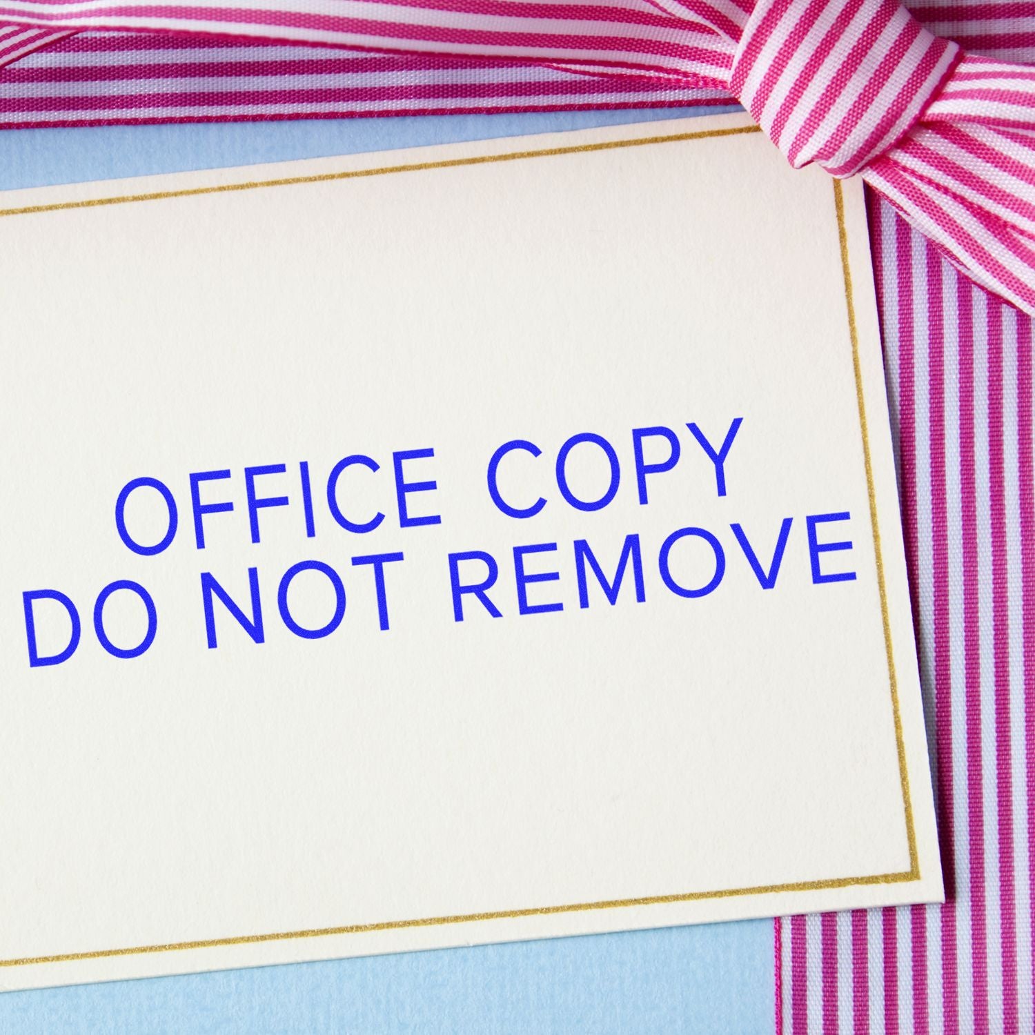 Large Pre-Inked Narrow Font Office Copy Do Not Remove Stamp used on a white card with pink and white striped ribbon in the background.