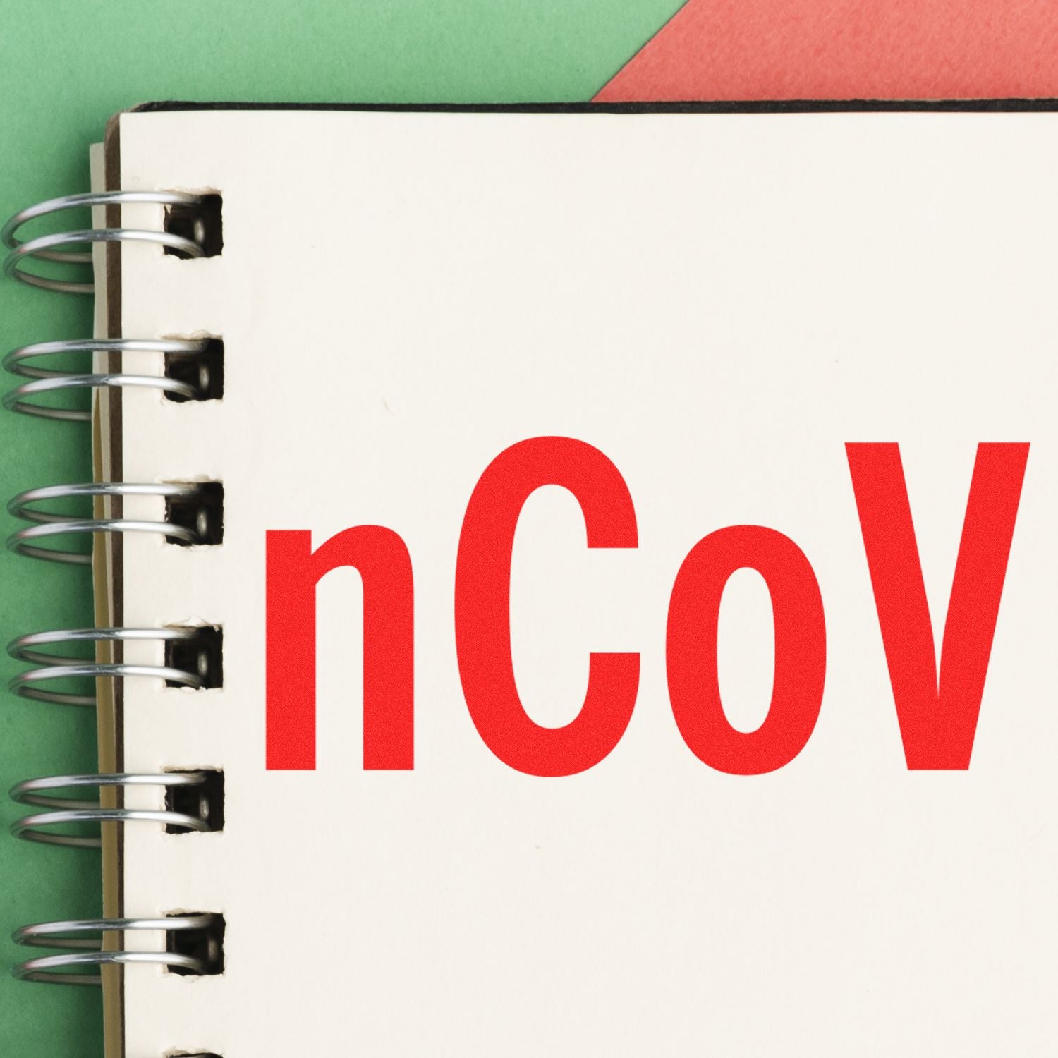 Large Pre-Inked nCov Stamp in red ink on a spiral-bound notebook, with a green and red background.