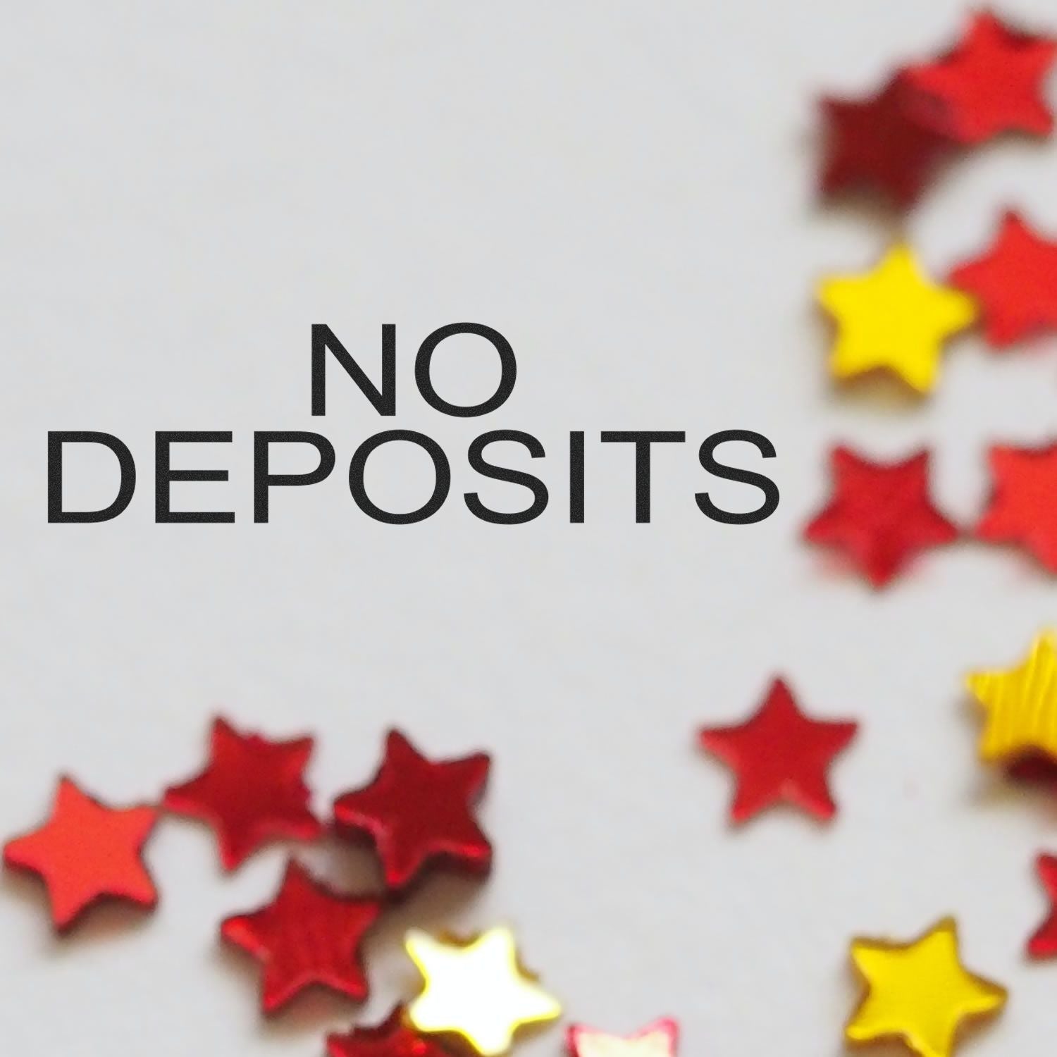 No Deposits rubber stamp with red and yellow star-shaped confetti scattered around on a white background.