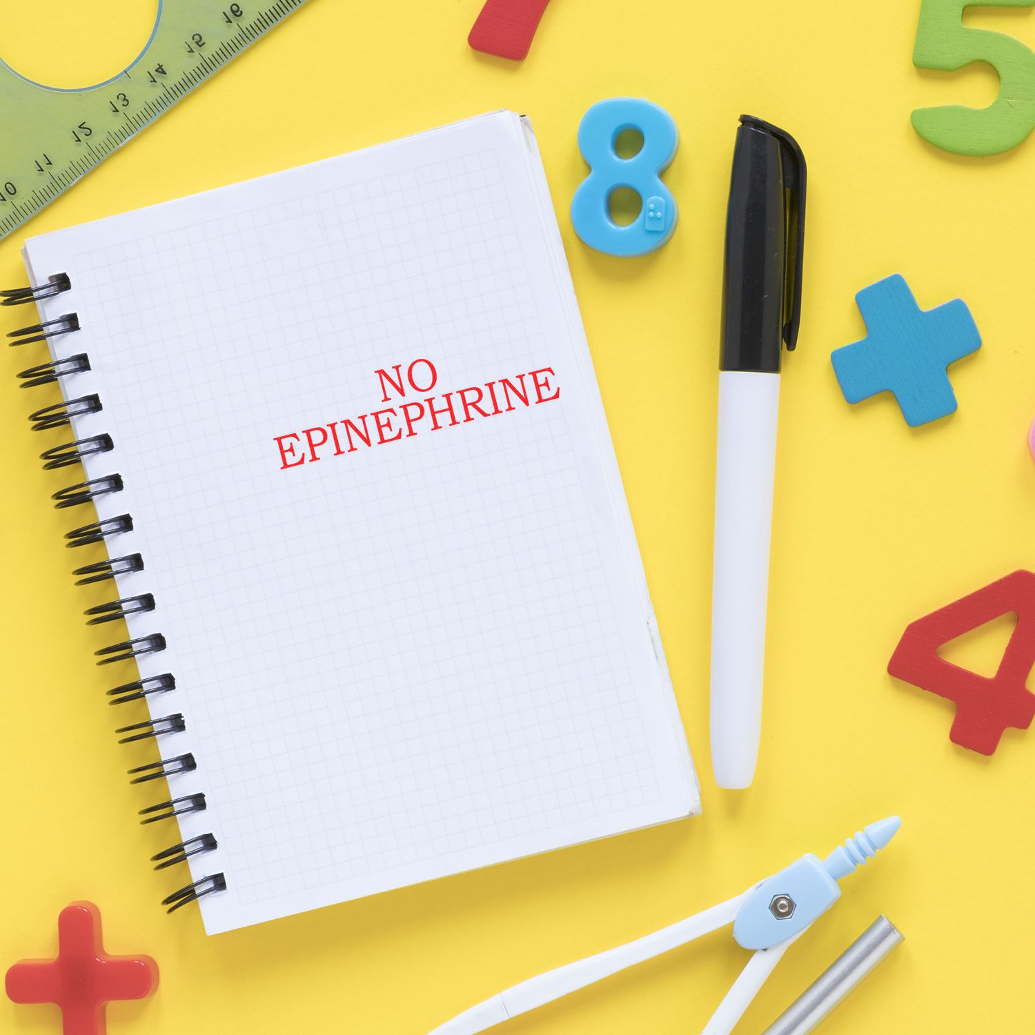 Large Pre-Inked No Epinephrine Stamp used on a notebook, surrounded by colorful numbers, a pen, a ruler, and a compass on a yellow background.