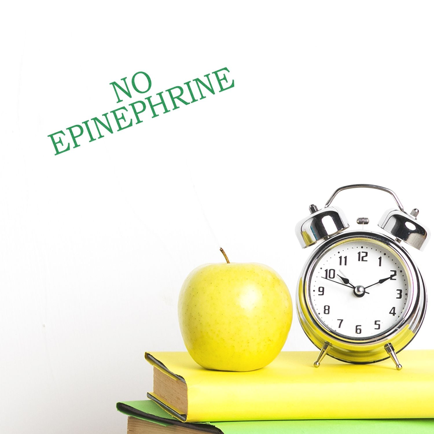 No Epinephrine Medical Rubber Stamp in green ink on white background, next to a clock, apple, and stack of books.