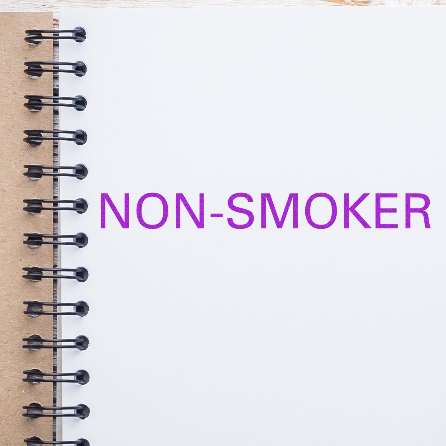 Non-Smoker Rubber Stamp impression in purple ink on a white spiral notebook page.