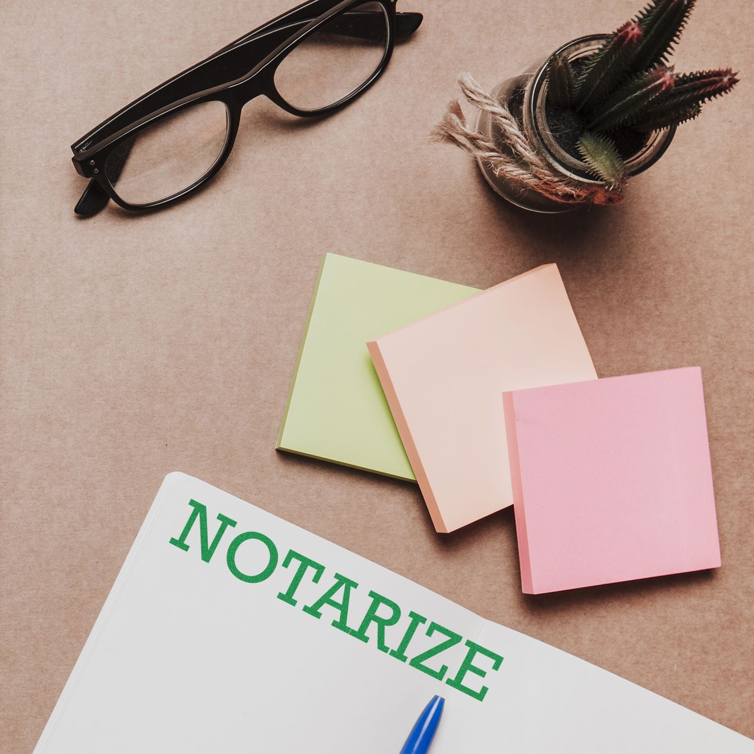 Large Notarize Rubber Stamp in use on a document with sticky notes, a pen, glasses, and a small plant on a brown desk.