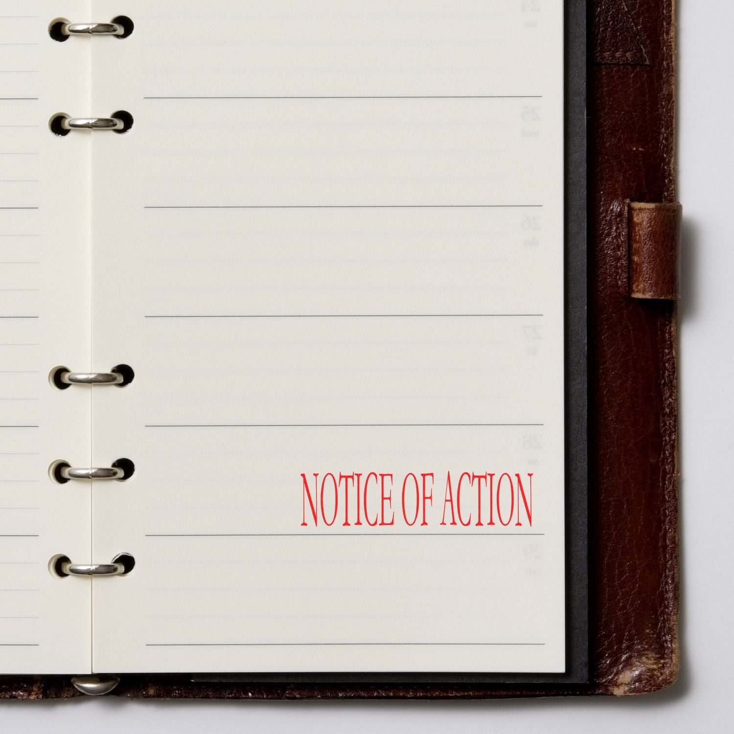 Large Pre-Inked Notice Of Action Stamp in red ink on a blank page of a leather-bound planner with metal rings.