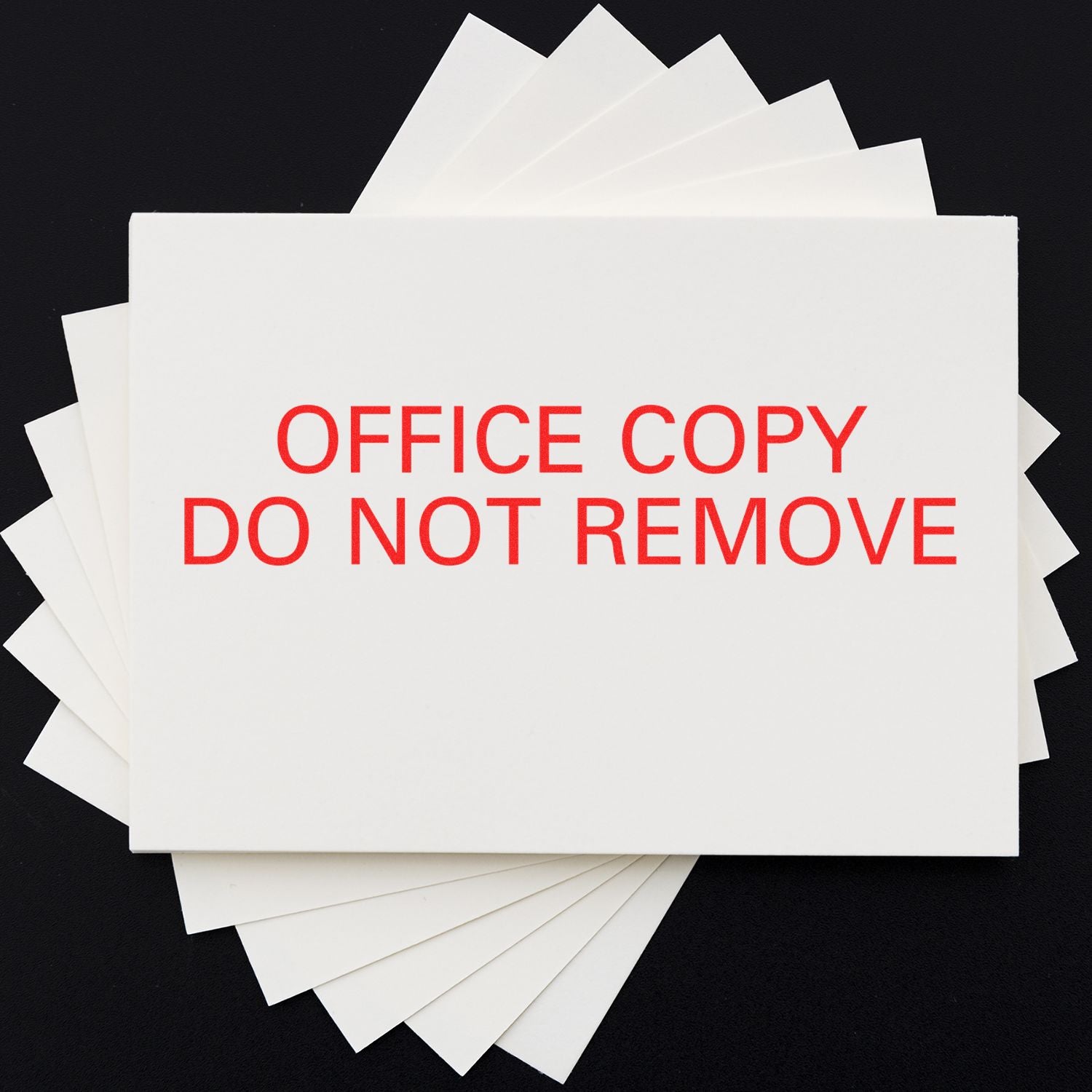 Office Copy Do Not Remove rubber stamp in red ink on a stack of white papers against a black background.