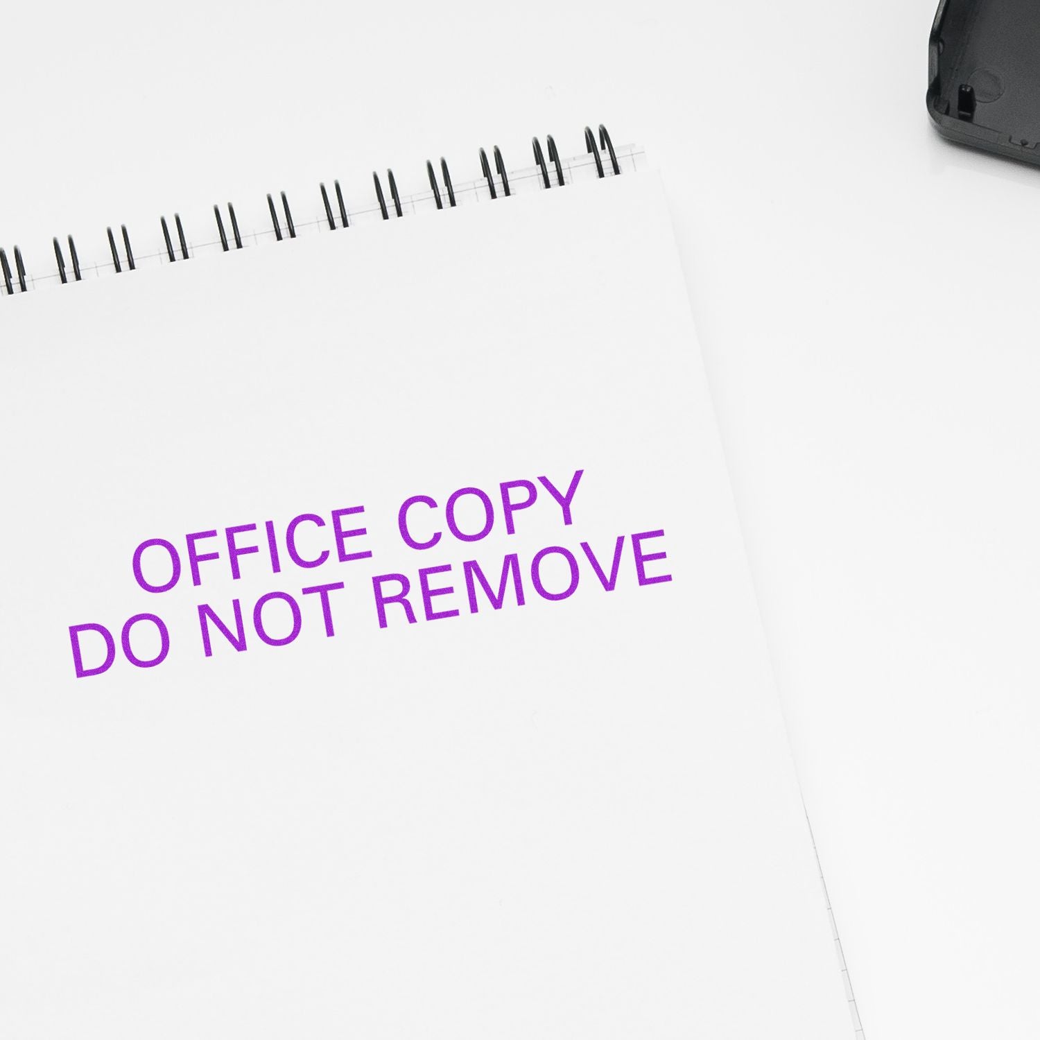 A white notebook stamped with OFFICE COPY DO NOT REMOVE in purple ink using the Large Office Copy Do Not Remove Rubber Stamp.