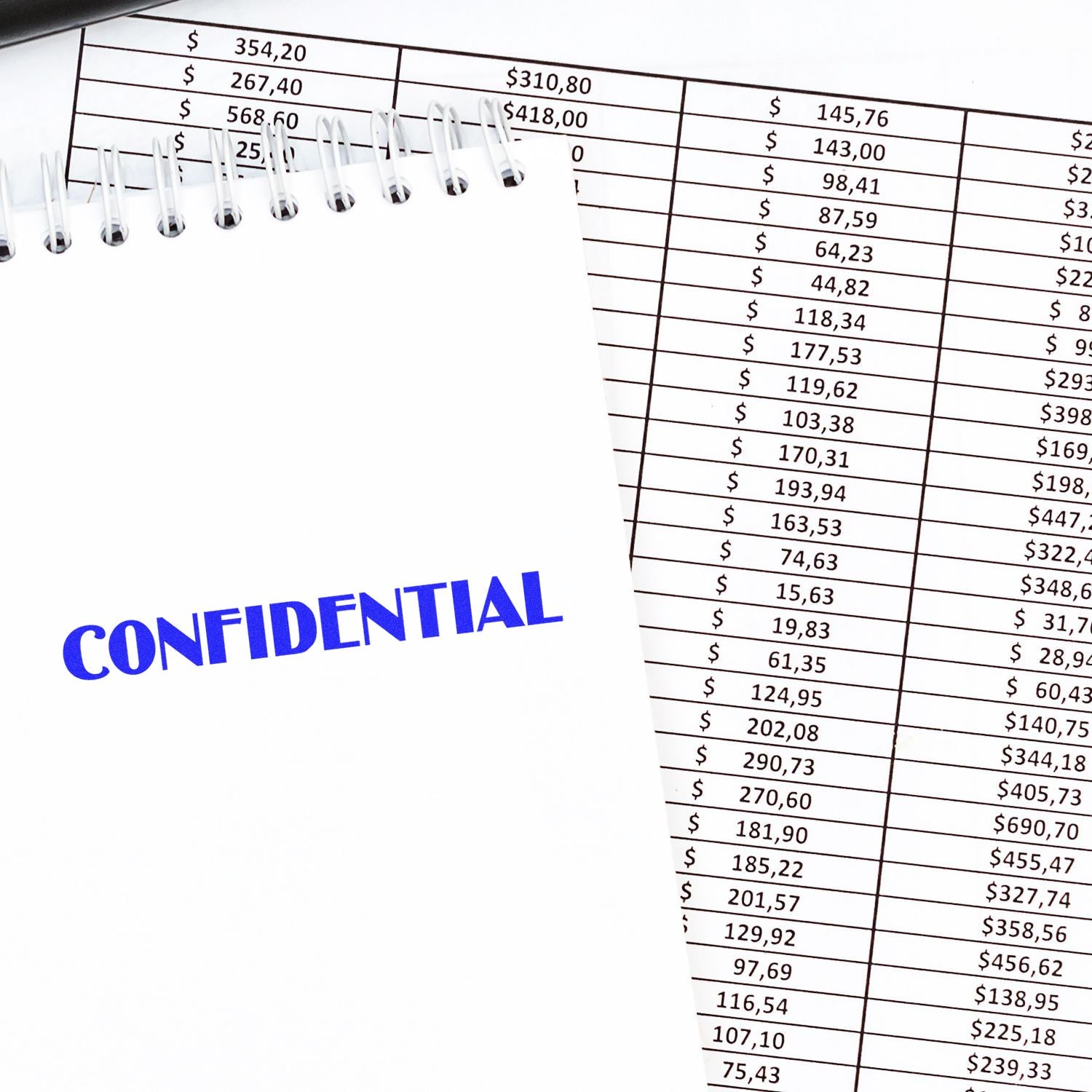 Large Self Inking Optima Confidential Stamp marking CONFIDENTIAL in blue ink on a white notepad, placed over a financial document.