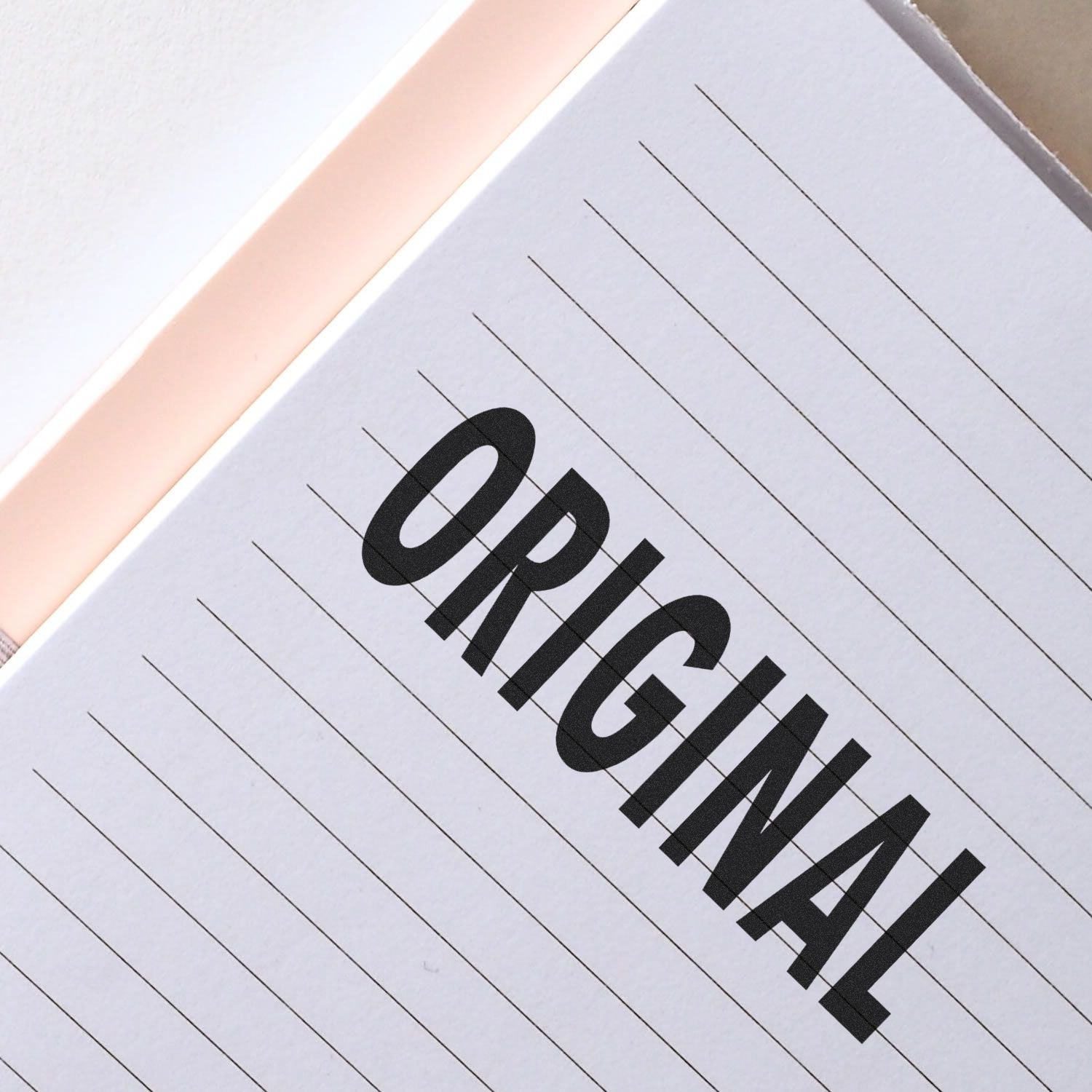 A Self Inking Original Stamp imprinting the word ORIGINAL in bold black letters on a lined white paper.