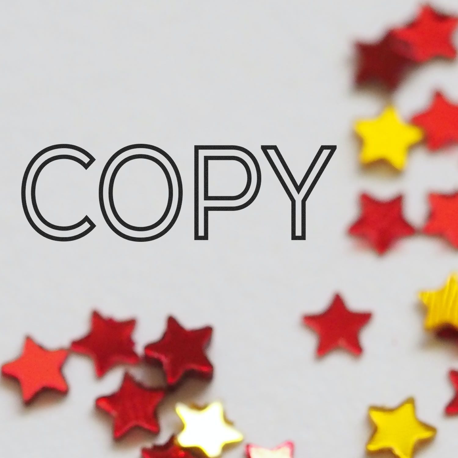 Red and yellow star confetti scattered around a 'COPY' mark made by a Slim Pre-Inked Outline Copy Stamp on a white surface.